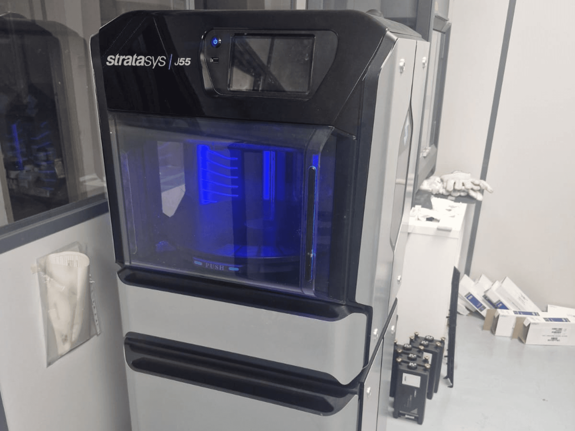 A Stratasys J55 Prime műanyag 3D nyomtató oldalnézetben, amely a karcsú kialakítást és a megvilágított nyomtatási területet mutatja be.