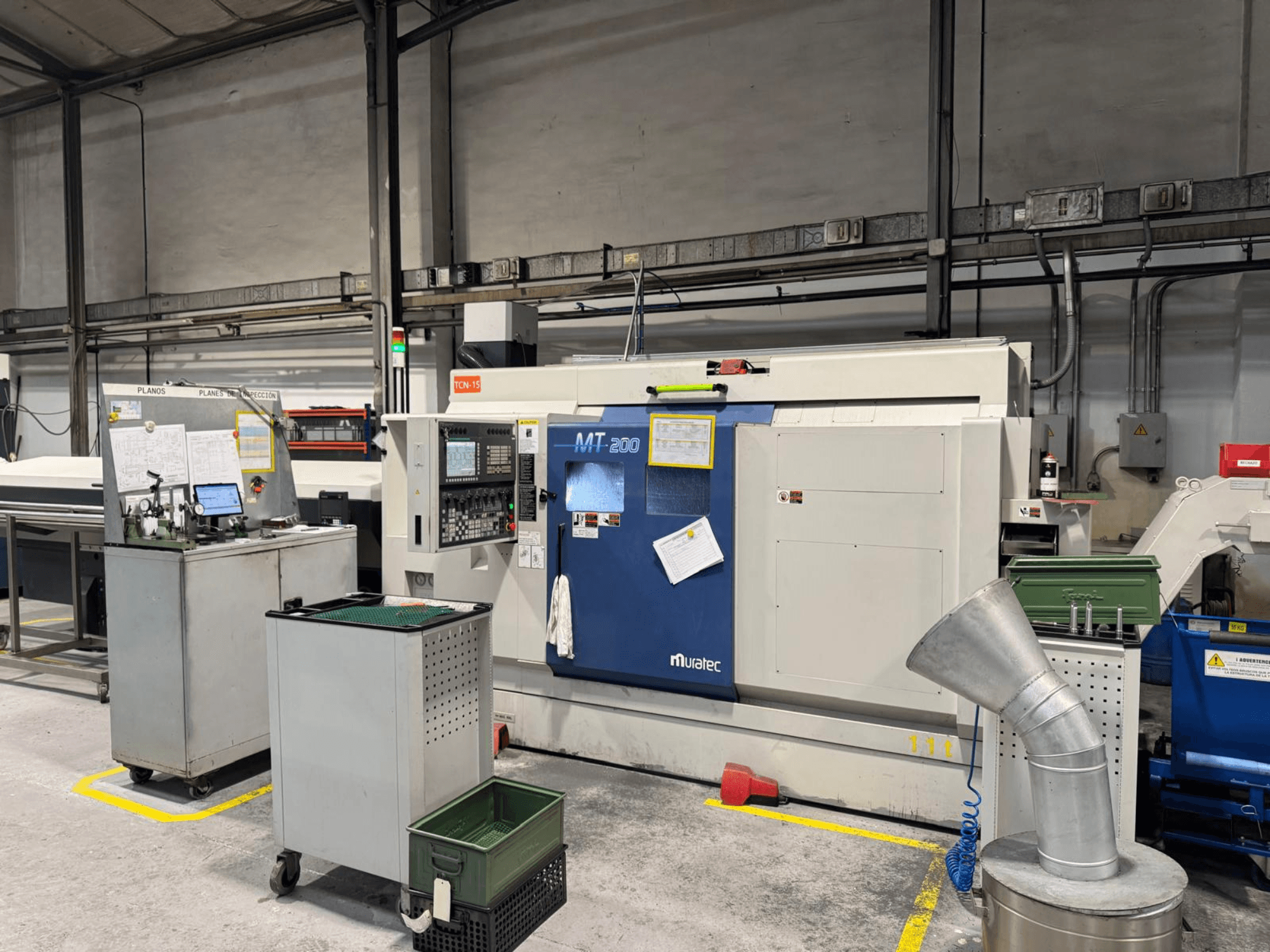 Muratec MT200 többorsós esztergagép gyári környezetben, szemből nézve, a vezérlőpanellel és a környező berendezésekkel.