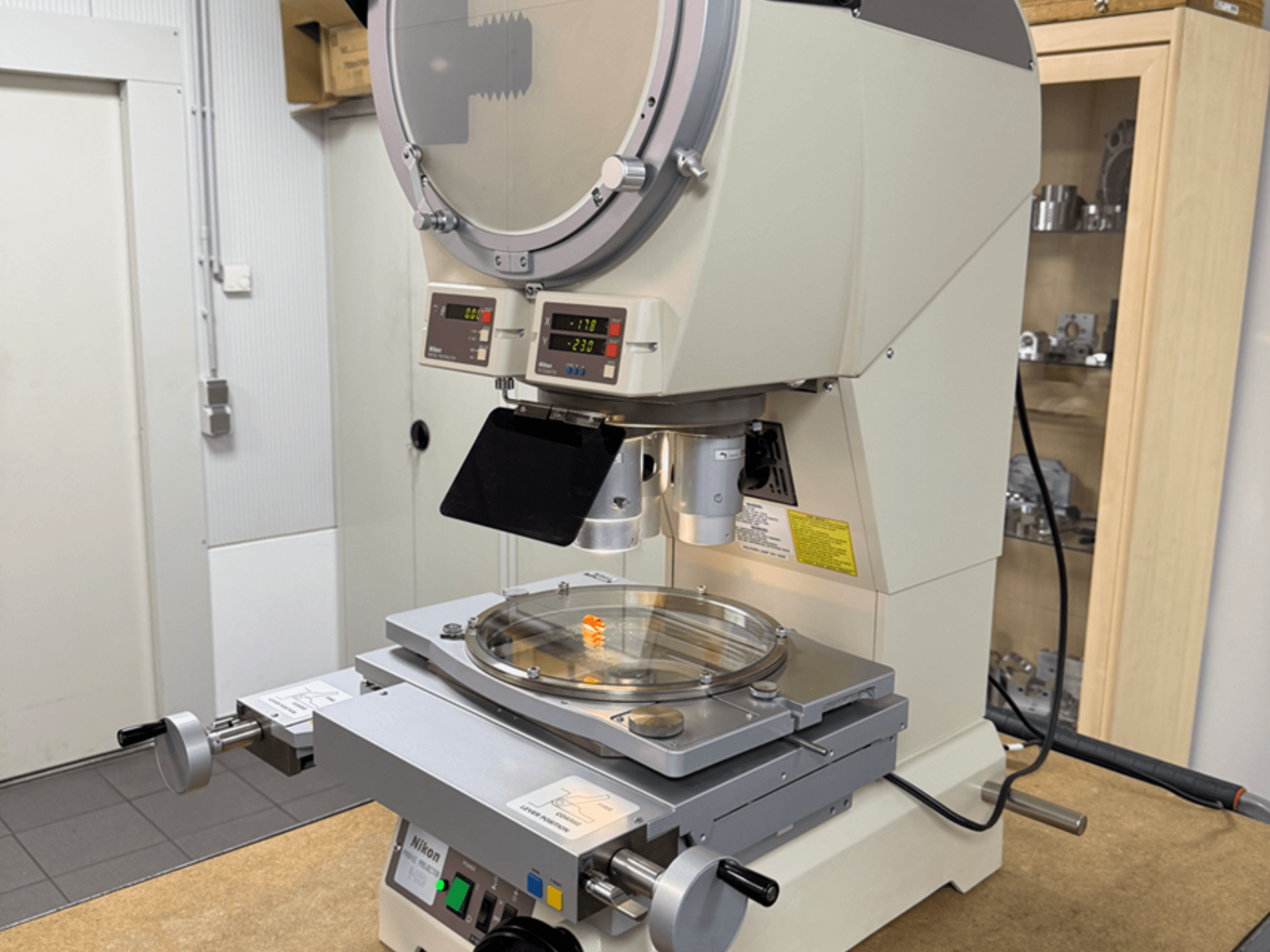 Nikon-mikroszkóp modell elölnézetből, digitális kijelzőkkel, állítható színpaddal és kör alakú üveglappal.