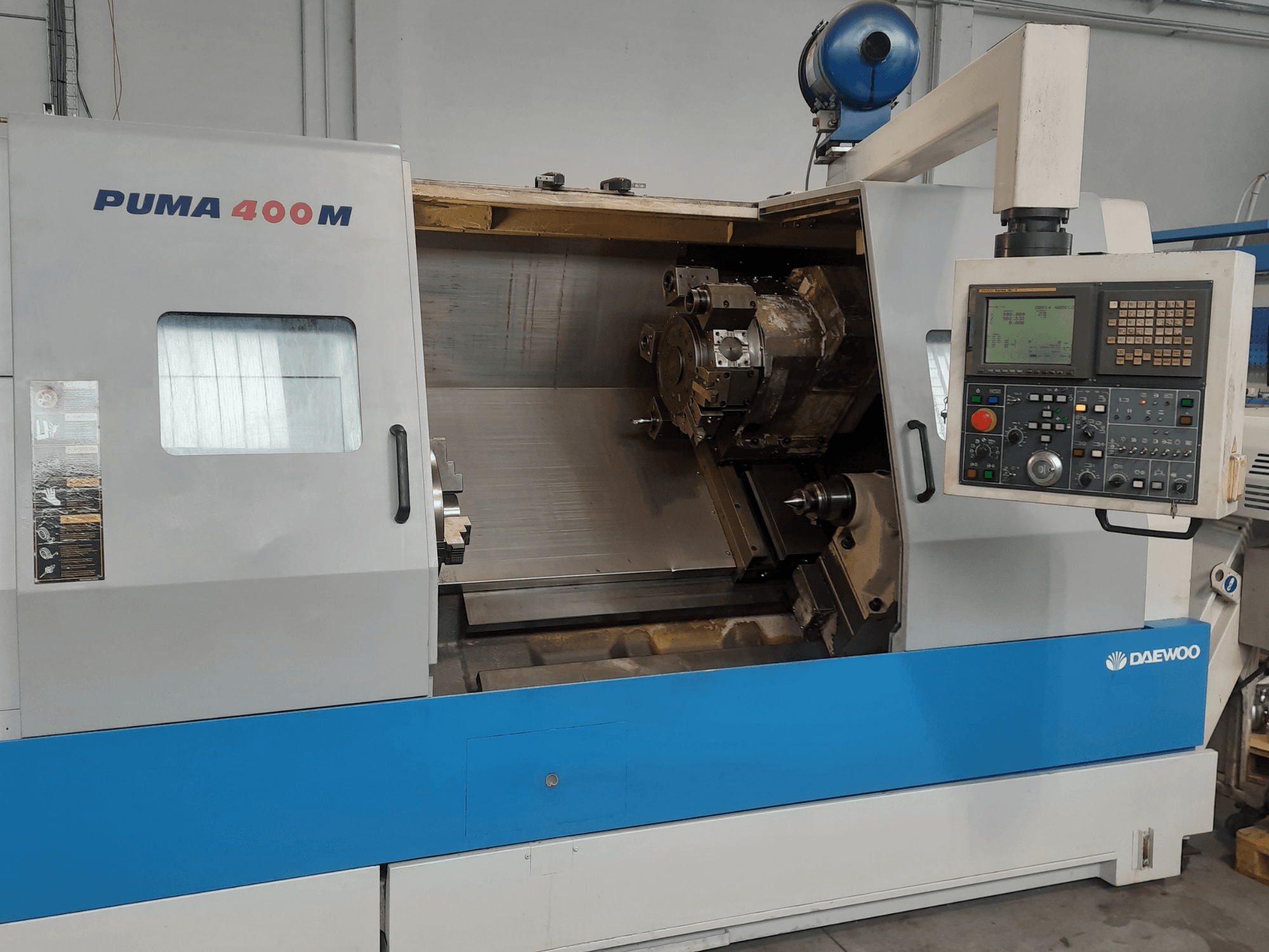 A DAEWOO PUMA 400MB vízszintes eszterga elölnézete, amelyen láthatók a kezelőszervek és a kamrában elhelyezett vágószerszám.