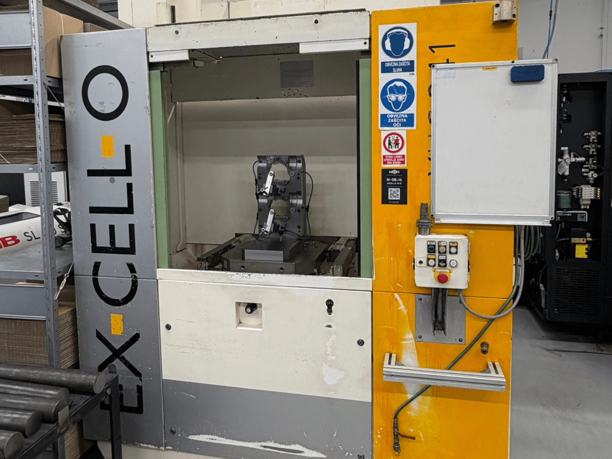 Az EXCELLO XHC 241 M/3 vízszintes megmunkálóközpont előlapja a látható vezérlőpanellel és a gép belsejével.