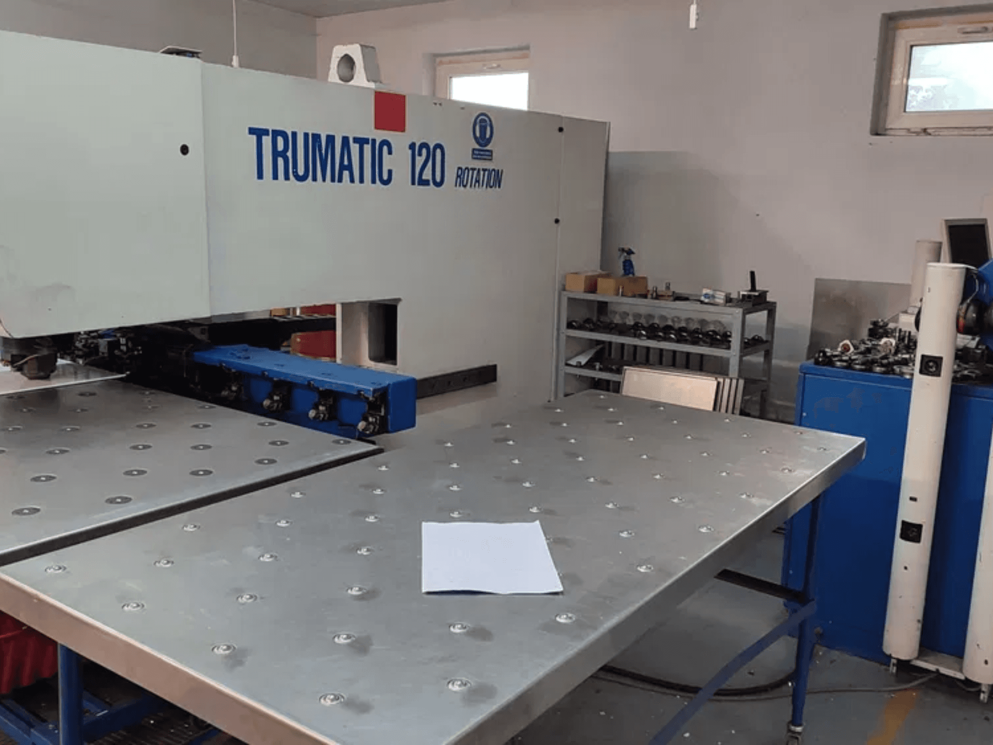 TRUMPF TRUMATIC 120R CNC lyukasztógép szemből nézve, egy fémasztal lyukakkal és egy üres lemezzel.