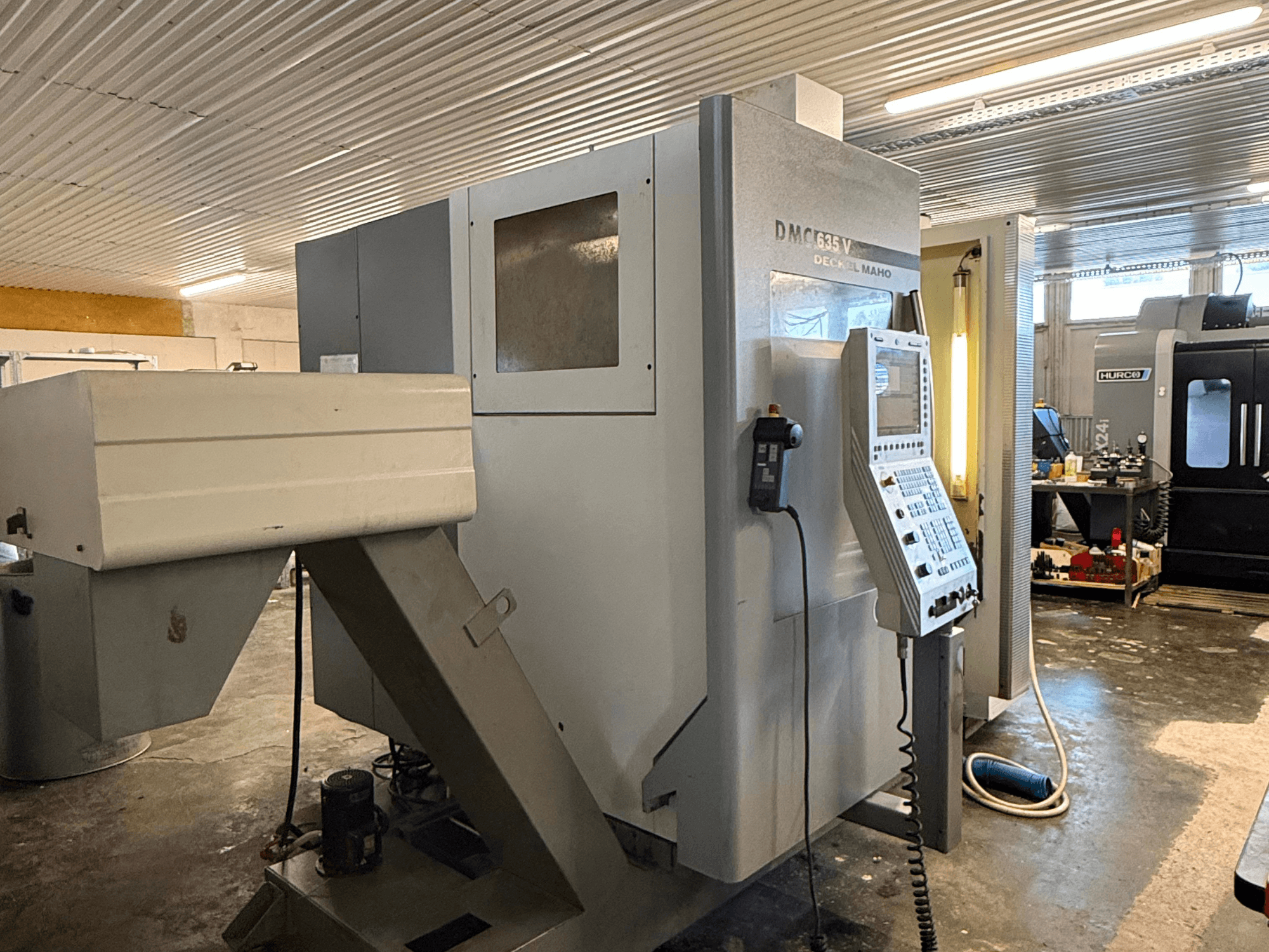 DMC G635V marógép egy műhelyben, elölnézetben a vezérlőpanel és a csatlakoztatott szerszámgépek láthatóak.