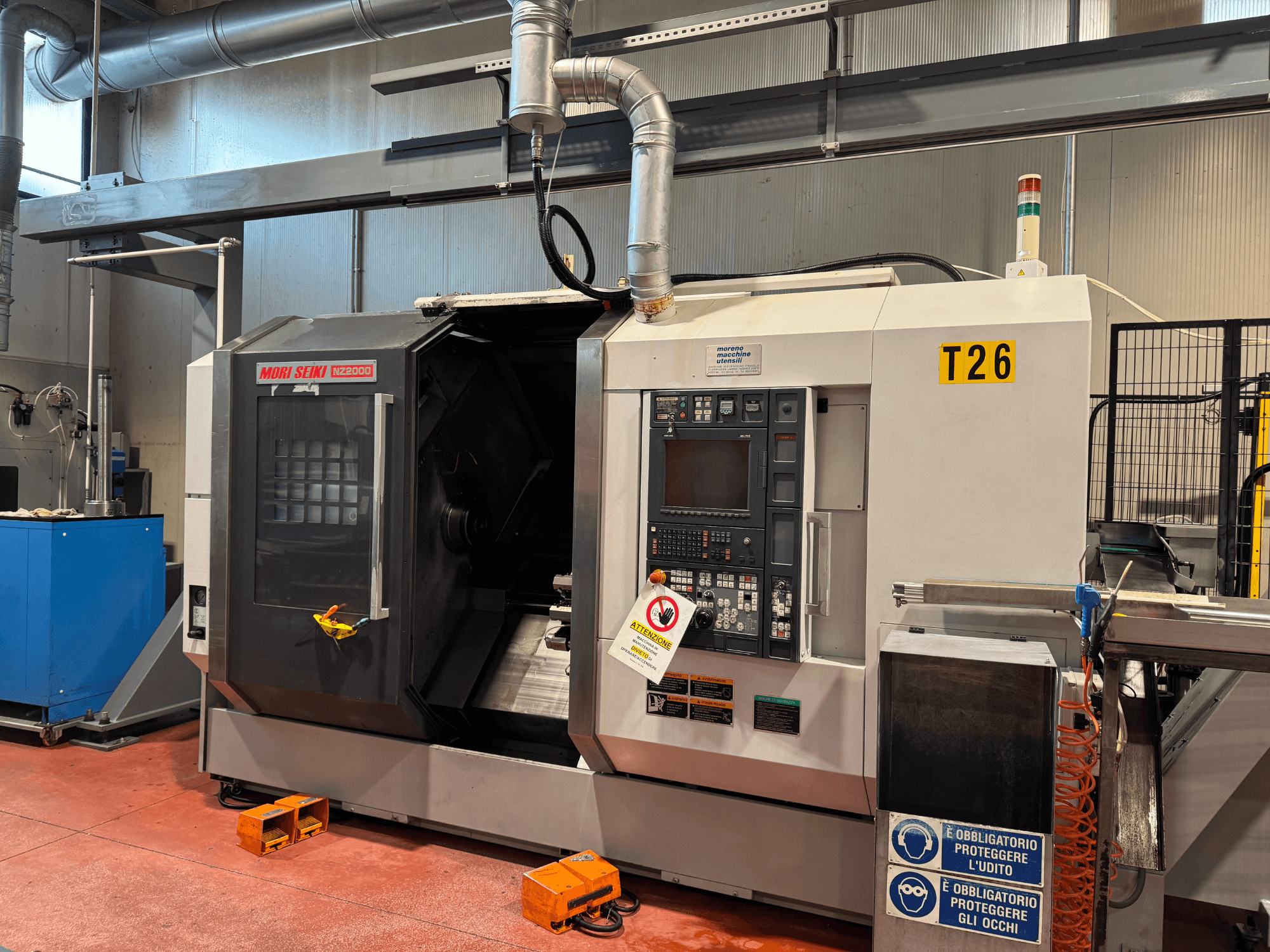 MORI SEIKI NZ-2000/T2/Y2 esztergálási központ, elölnézet, vezérlőpanel, biztonsági jelzések és ipari beállítások.