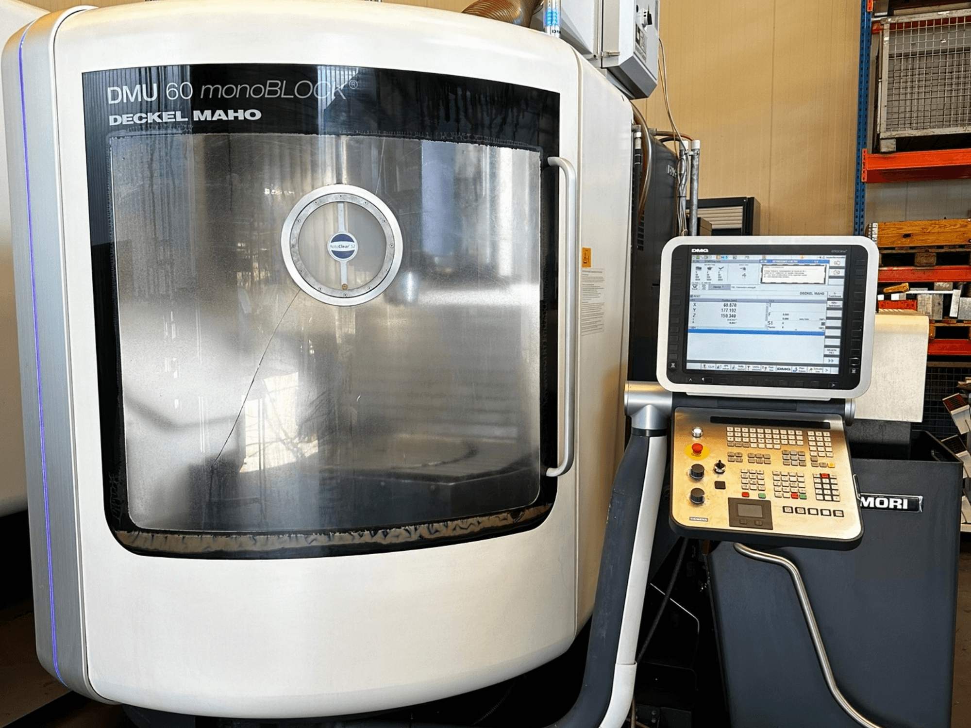 DMG MORI DMU 60 monoBLOCK függőleges megmunkálóközpont, előlnézet, érintőképernyős kezelőpanel és fényvisszaverő ablak.