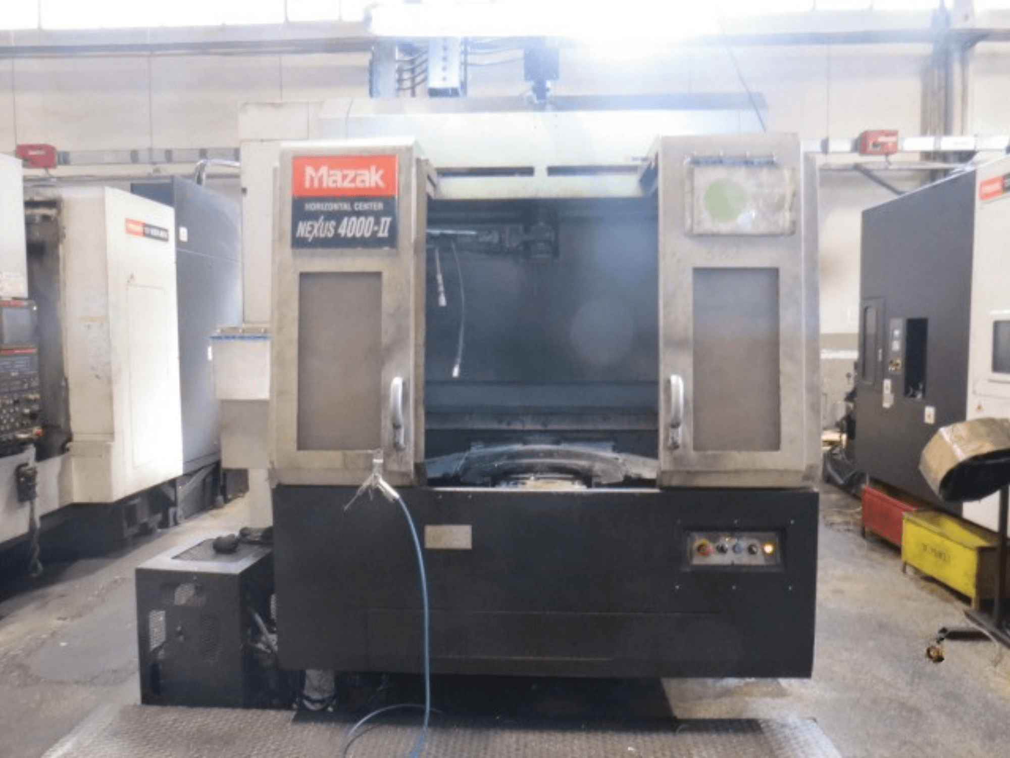 Mazak NEXUS 4000 II vízszintes megmunkáló központ, elölnézet, amelyen látható a vezérlőpanel, a hűtőfolyadék-ellátás és a nyitott munkaterület.