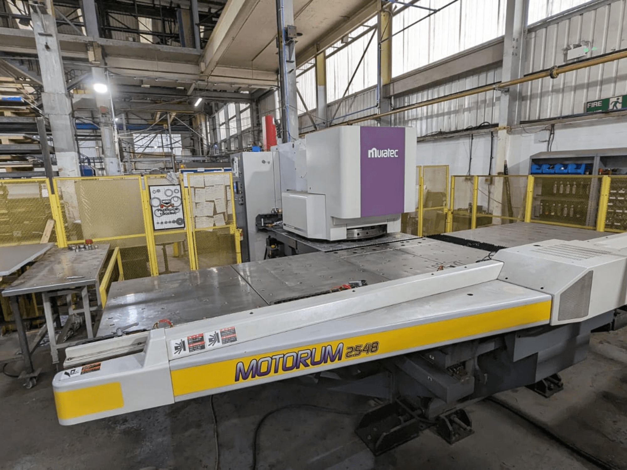 Muratec MOTORUM 2548 CNC lyukasztógép, elölnézet, amelyen a vezérlőpanel és a munkapad látható gyári környezetben.