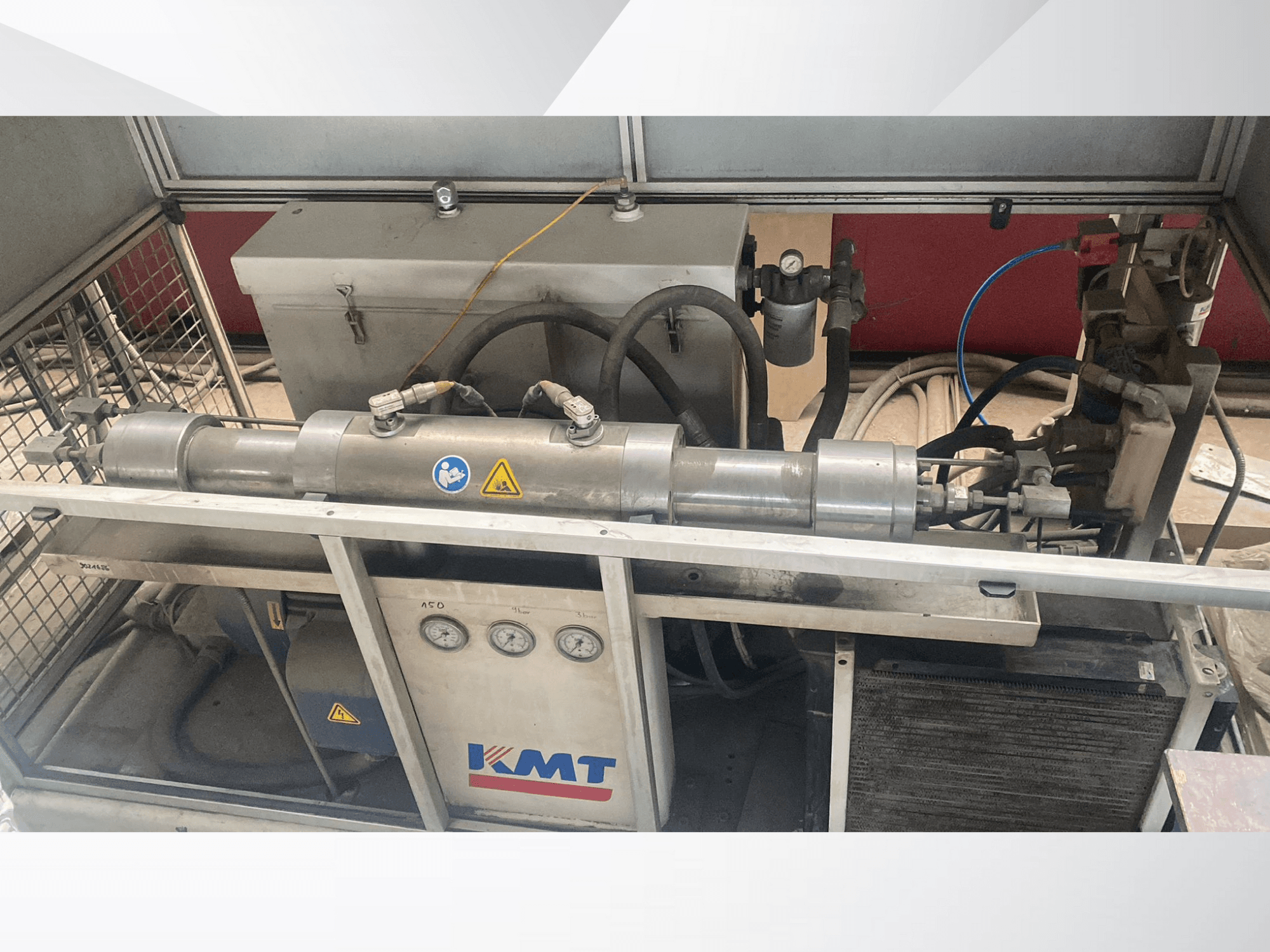 KMT hidraulikus gép elölnézetben, nyomásmérőkkel, tömlőkkel és fémházzal, ideális ipari alkalmazásokhoz.