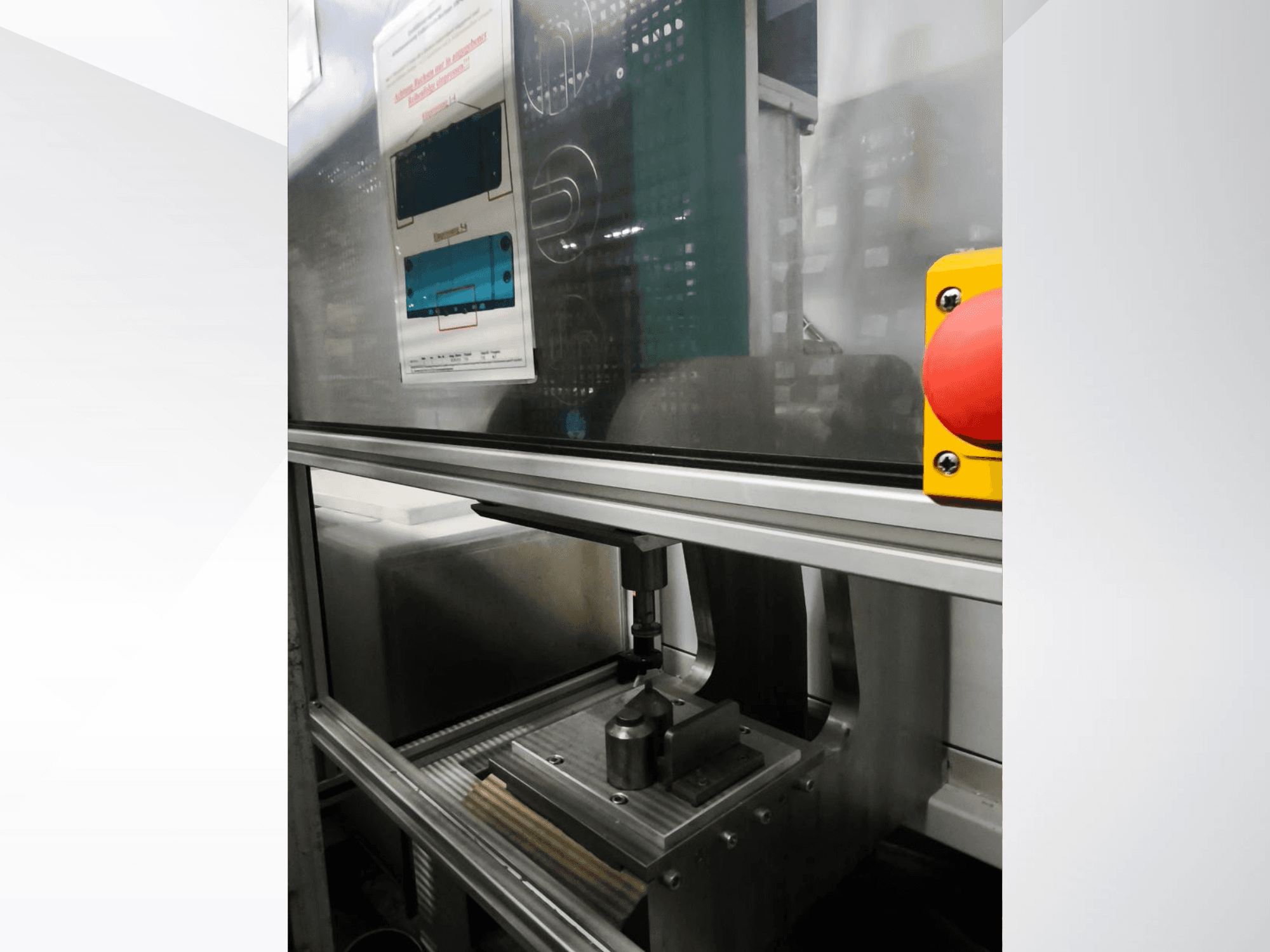 Az EMS Automation Buchsenpresse szerszámgép elülső nézete, a présmechanizmus és a biztonsági gomb bemutatásával.