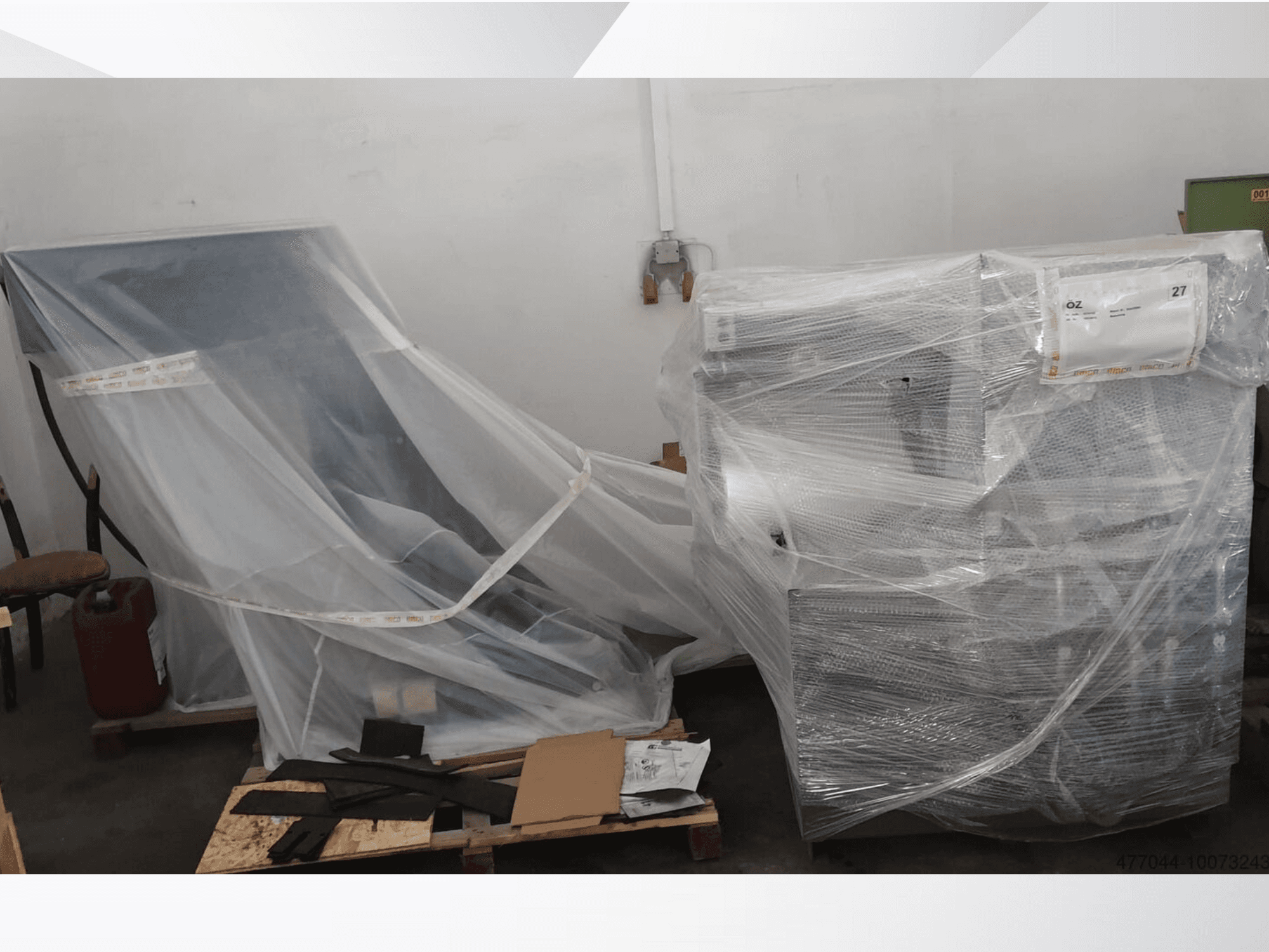 Műanyagba csomagolt ipari berendezés, egy szék és egy gép, oldalnézetből, raktári környezetben.