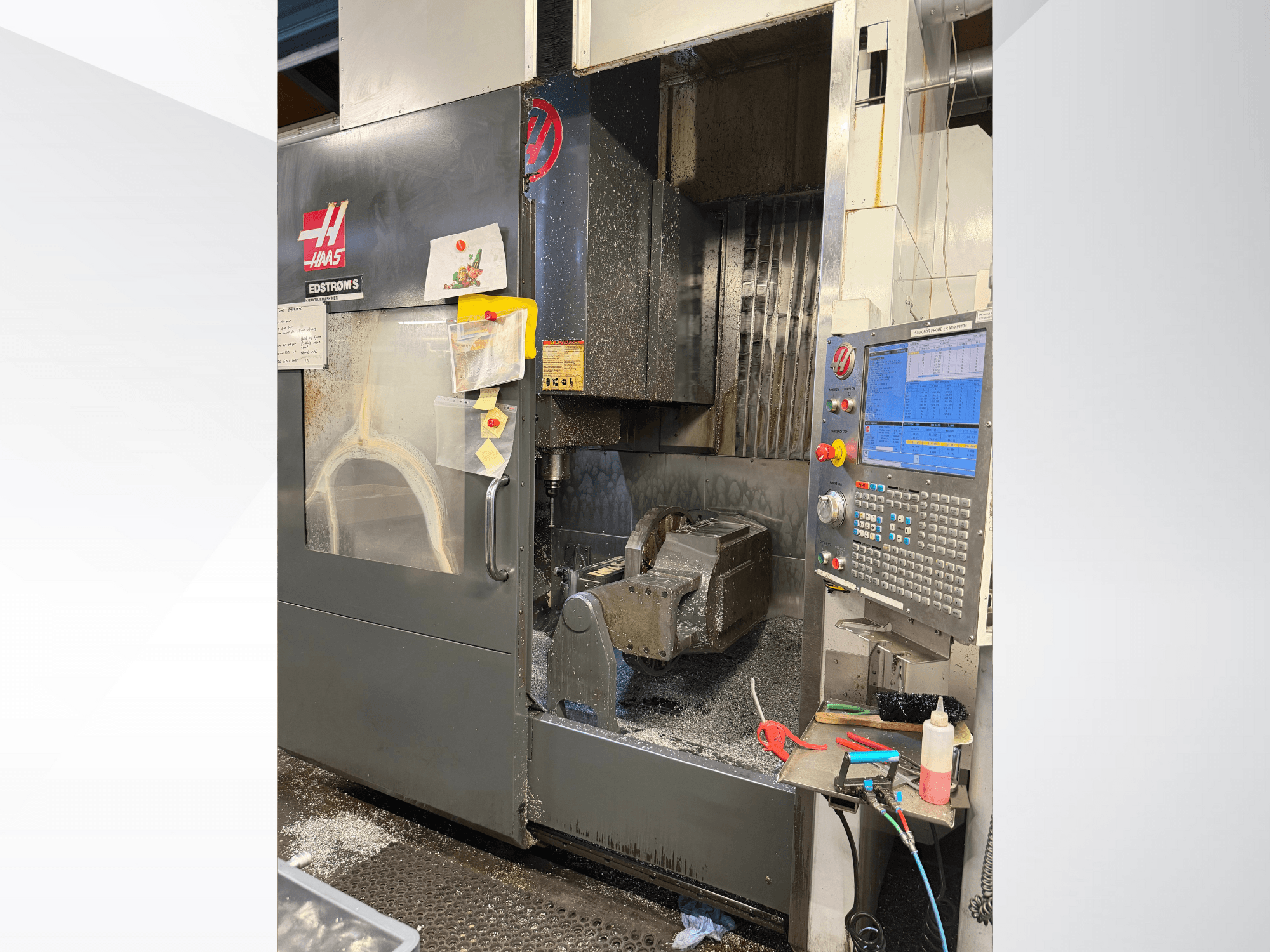 Haas CNC-gép EDSTROM S modell, előlnézet, a fém munkadarab, a vezérlőpanel és a fémforgácsok a belsejében.