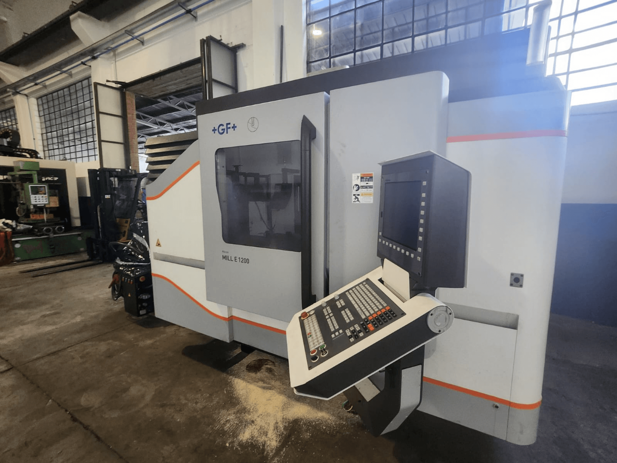 GF MILL E1200, a marógép elülső nézete a kezelőpanellel, a kijelzővel és a biztonsági címkékkel, műhelyben.