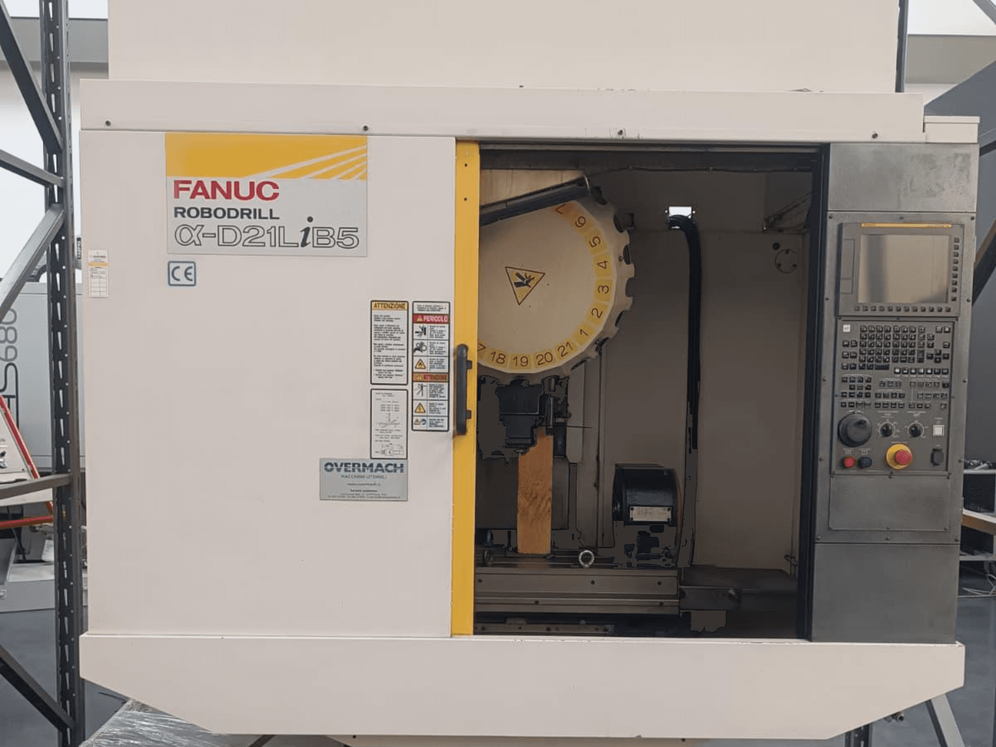 FANUC Robodrill α-D21LiB5, előlnézet; CNC-gép szerszámtartóval, vezérlőpanellel és biztonsági figyelmeztetésekkel.
