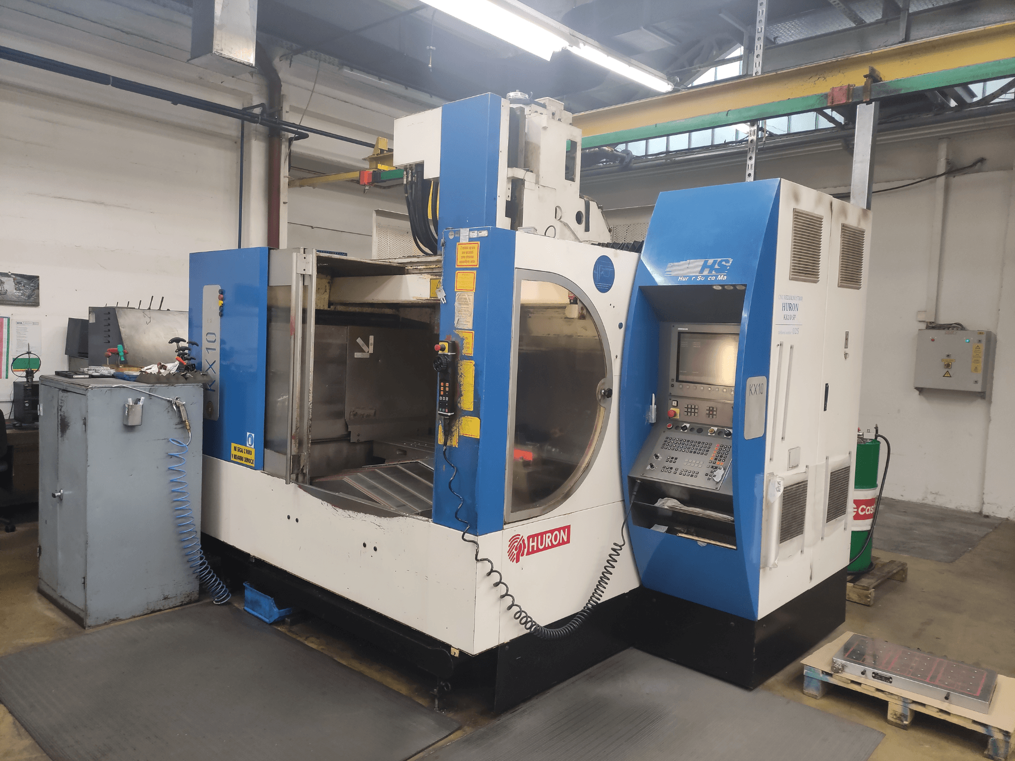 HURON KX10 CNC-gép egy műhelyben, elölnézetben, vezérlőpanel és nagy megmunkálási nyílás.