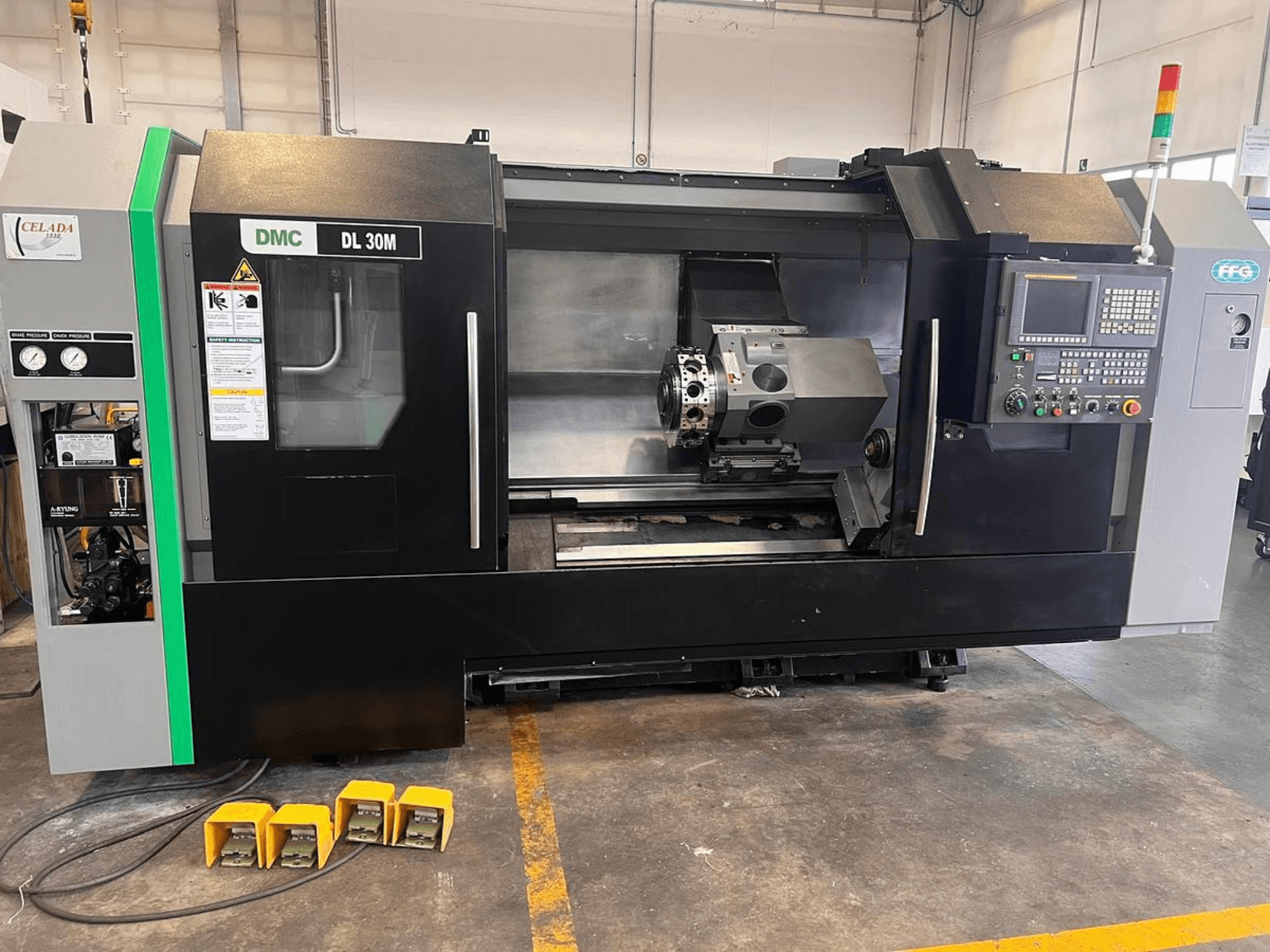 DMC DL 30M CNC-gép oldalnézetben, amelyen a vezérlők, az orsó és a három lábpedál látható a padlón.