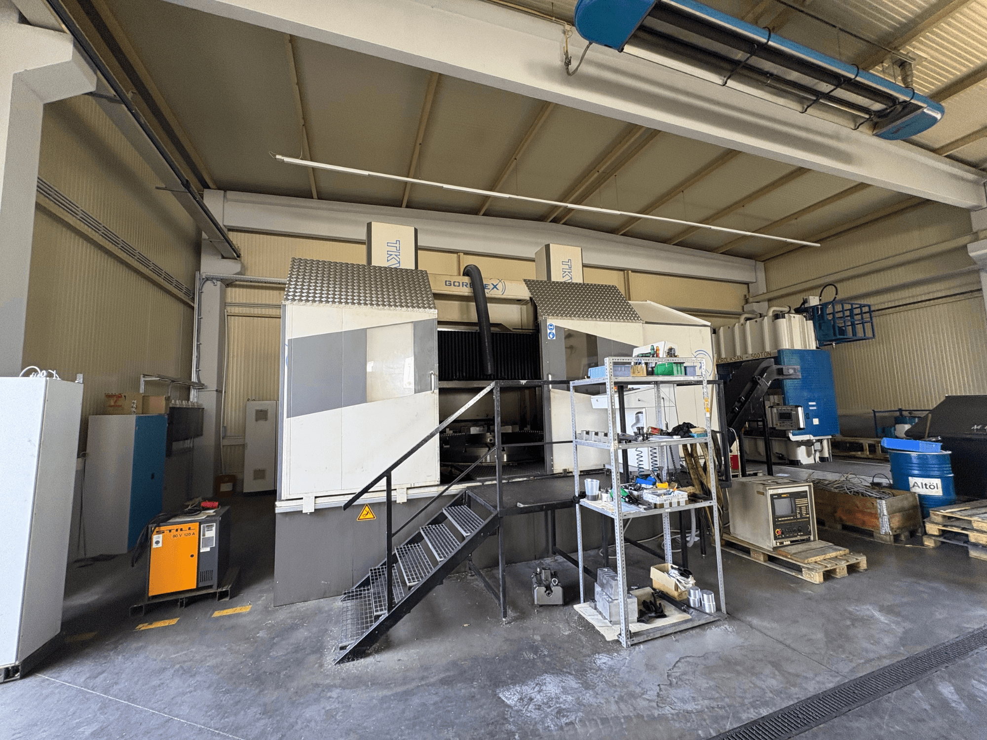 Ipari megmunkáló berendezés GORAT X géppel, oldalnézet; szerszámokat, vezérlőpanelt és berendezéseket tartalmaz a polcokon.