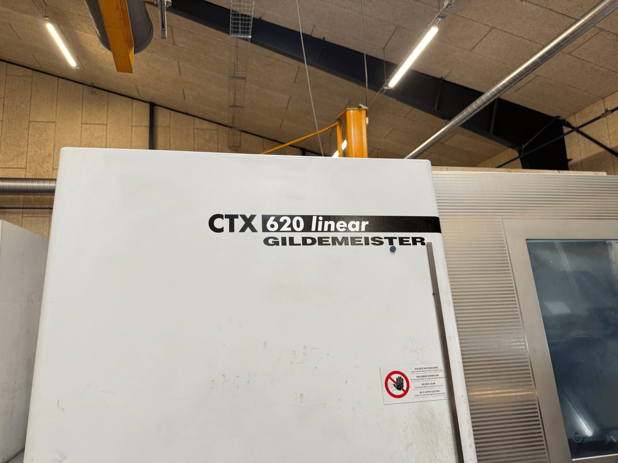 CTX 620 Linear Gildemeister gép oldalnézetben, fehér külsővel és biztonsági figyelmeztető címkékkel.