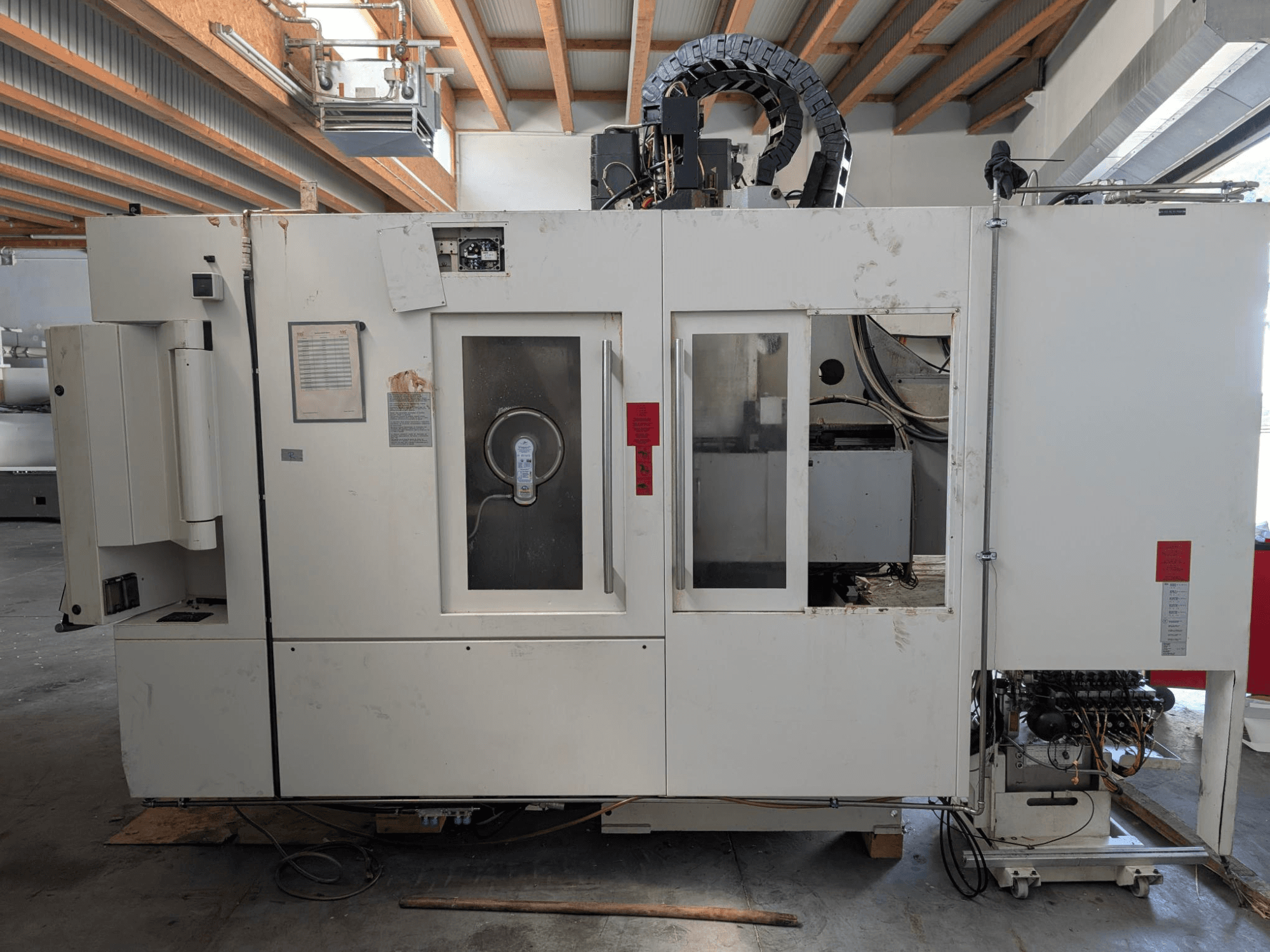 STAMA MC 326 függőleges megmunkálóközpont, oldalnézet a vezérlőpanel, az orsó területe és a gépen lévő különböző címkékkel.