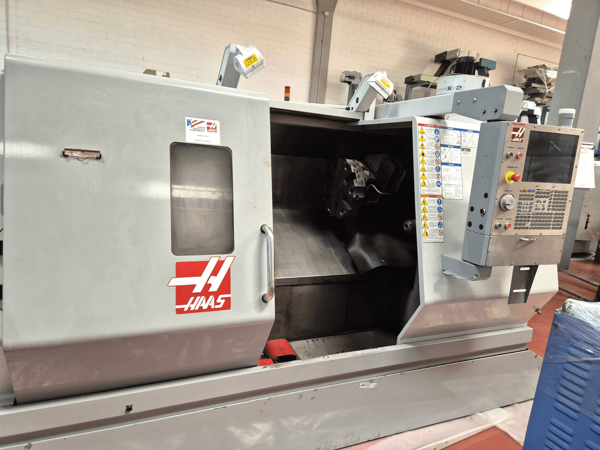 Haas SL 30TBHE vízszintes eszterga, elölnézet, amelyen láthatók a kezelőszervek és a megmunkálási műveletekhez szolgáló nyitott munkatér.