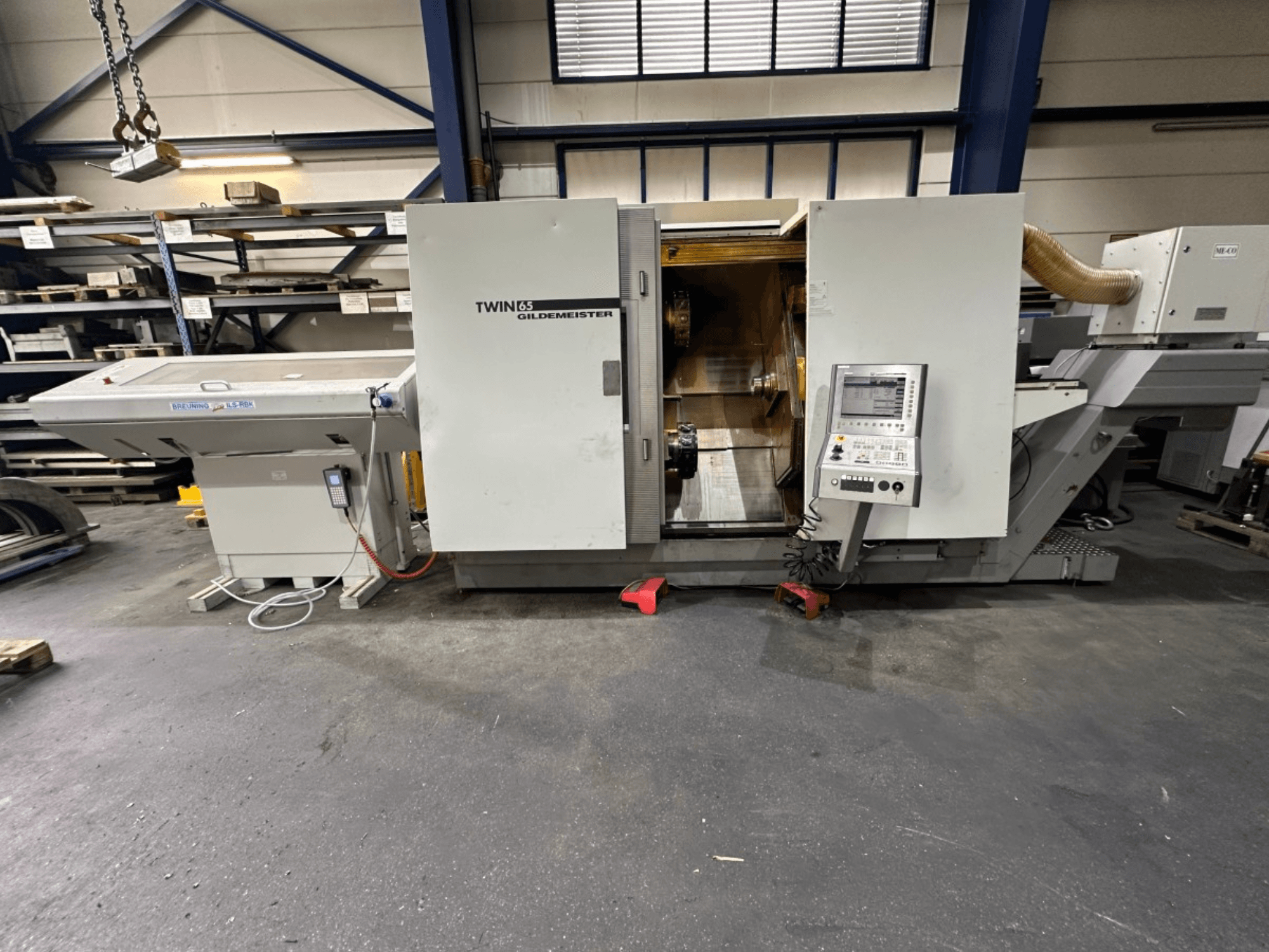 Gildemeister TWIN 65 vízszintes esztergagép, elölnézet; vezérlőpanel és látható belső tér az alkatrészek megmunkálásához.