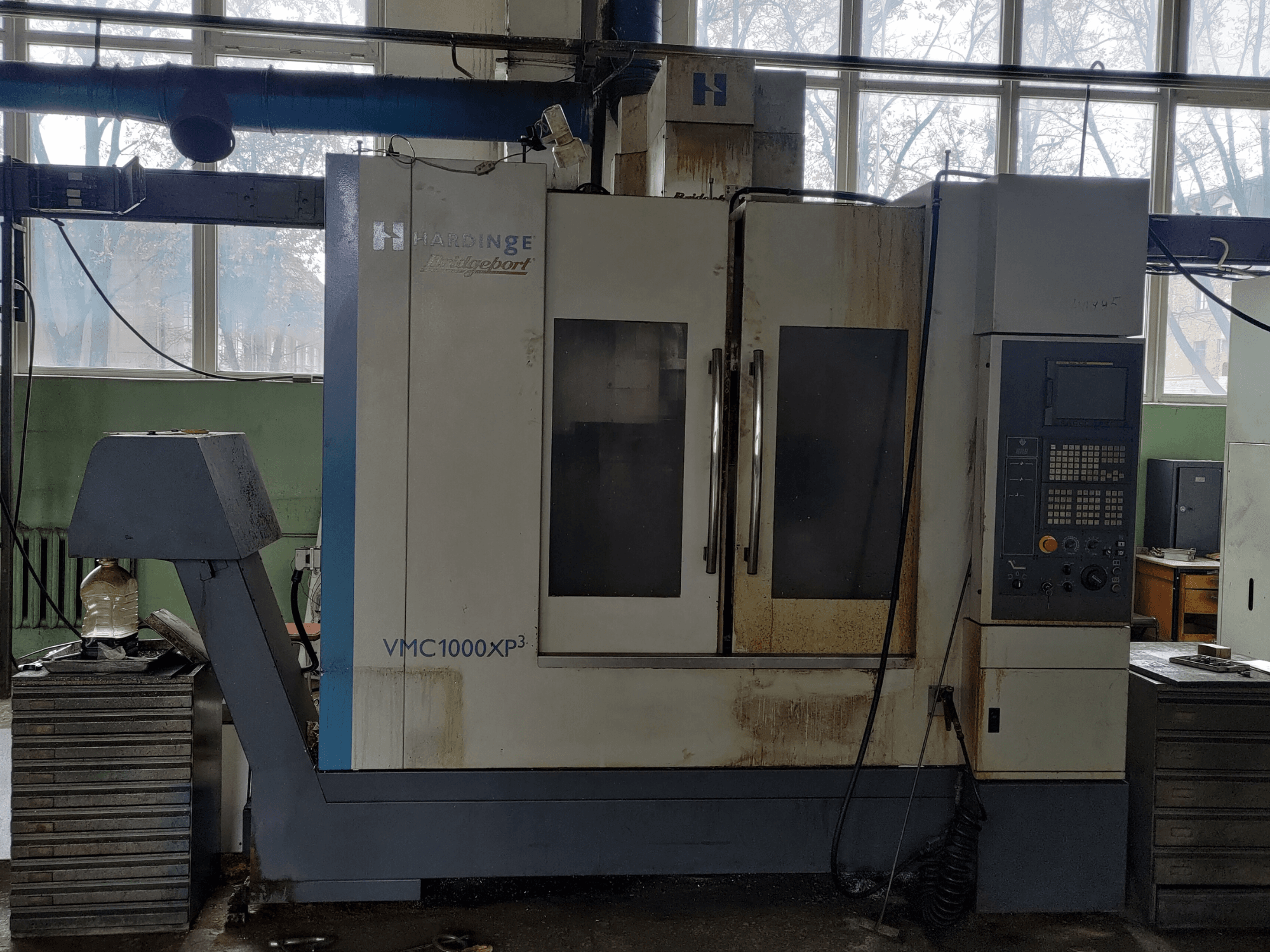 A Bridgeport VMC1000 XP3 függőleges megmunkáló központ elölnézete, amelyen látható a vezérlőpanel és enyhe kopásnyomok.