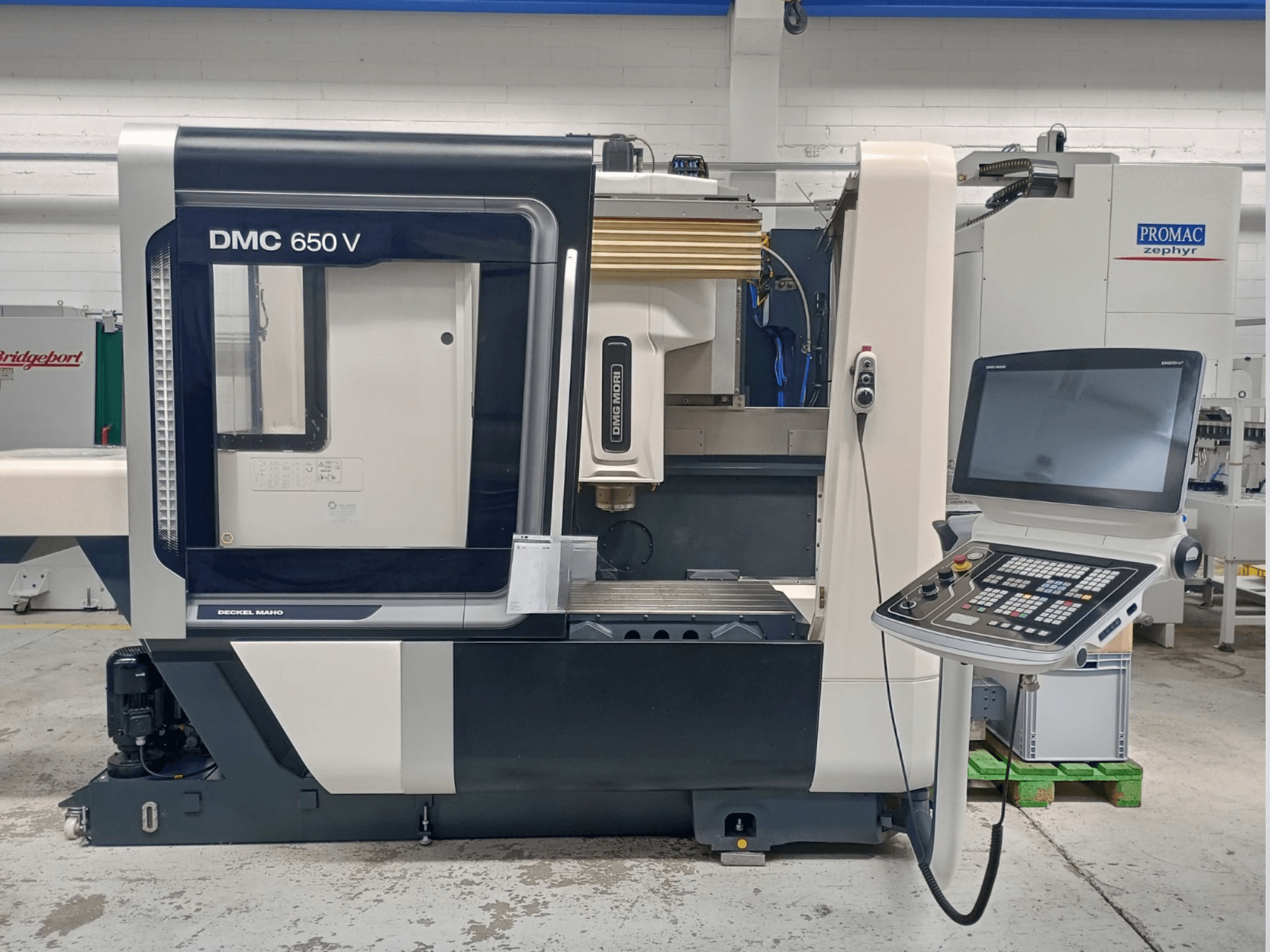 Decker Maho DMC 650 V CNC-gép oldalnézetben, gombokkal és képernyővel ellátott kezelőpanellel, ipari környezetben.