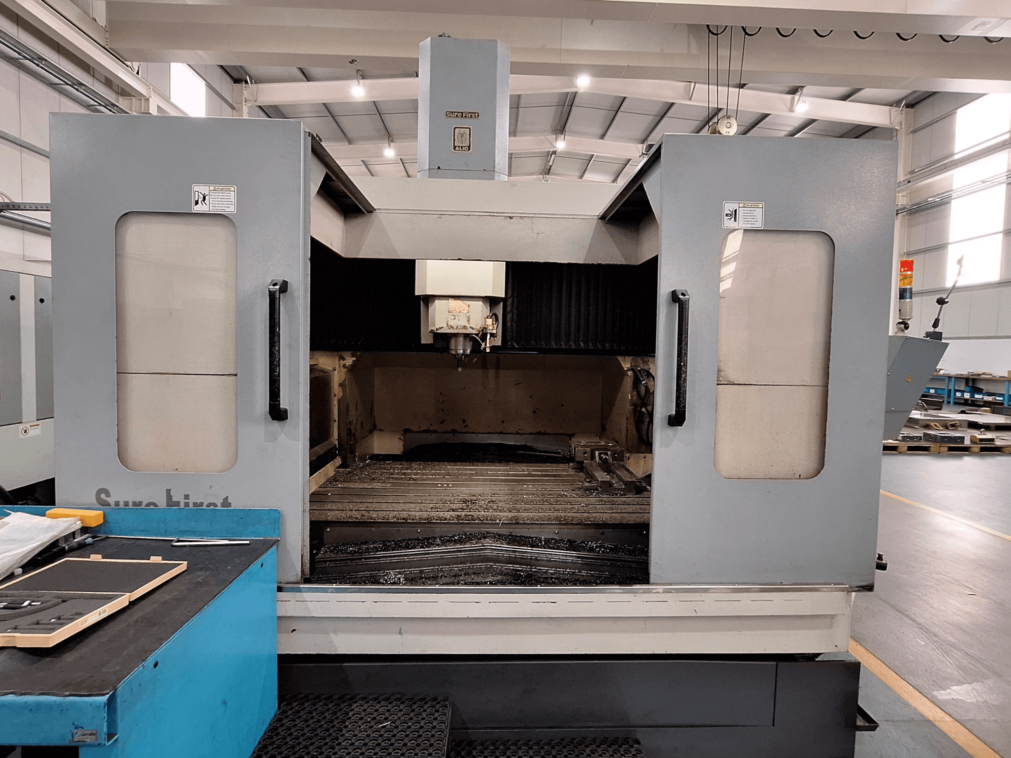 Függőleges megmunkálóközpont Sure First QM-1836, elölnézetben a szerszámfej és az üres munkaterület, modern ipari környezetben.