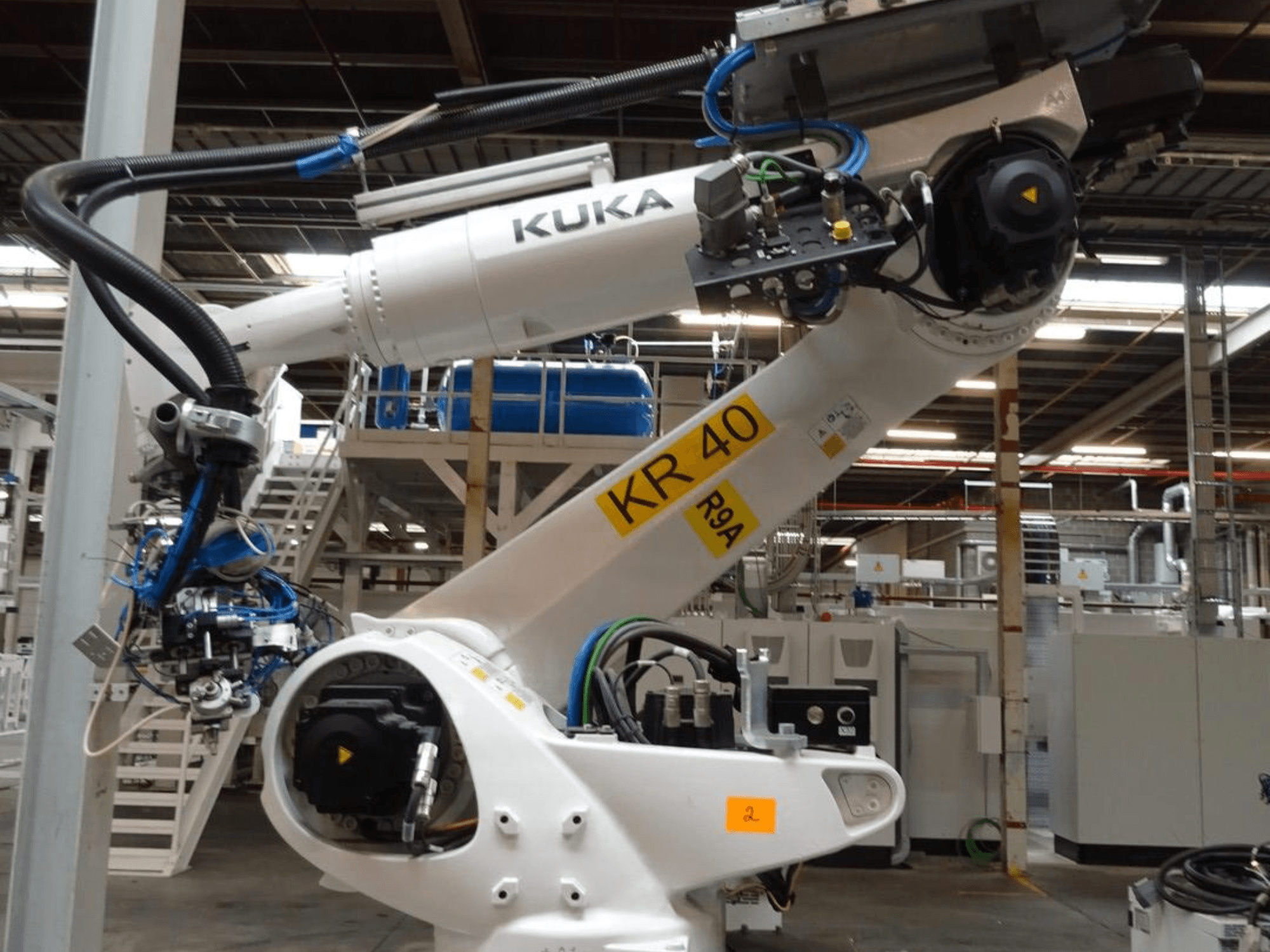 KUKA KR 120 R3100-2 robotkar oldalnézetben, a vezérlőpanel és a mechanikus alkatrészek bemutatásával, ipari környezetben.