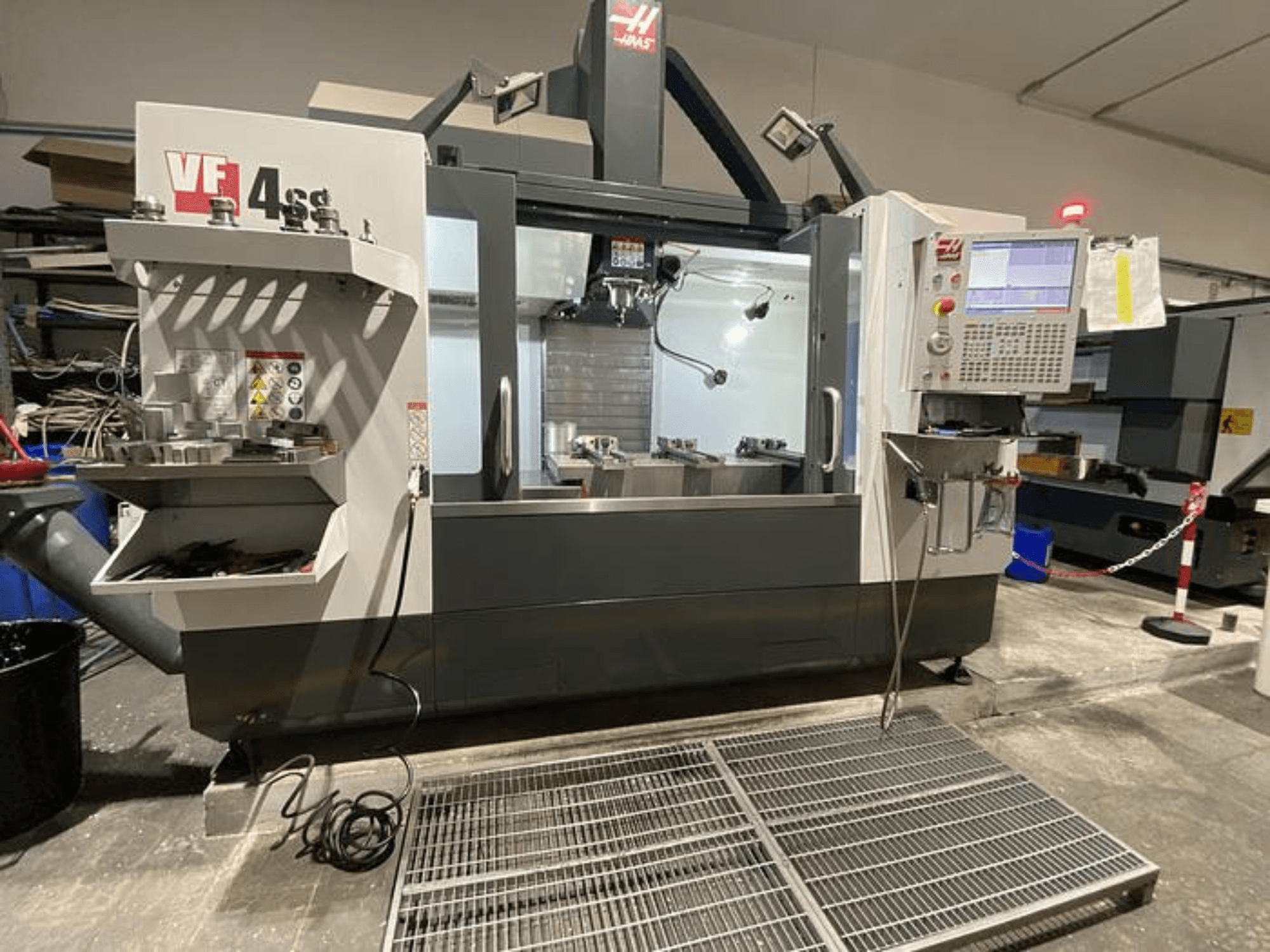 Haas VF-4SS CNC marógép, elölnézetben, szerszámtárolóval, vezérlőpanellel és látható munkaterülettel műhelyben.