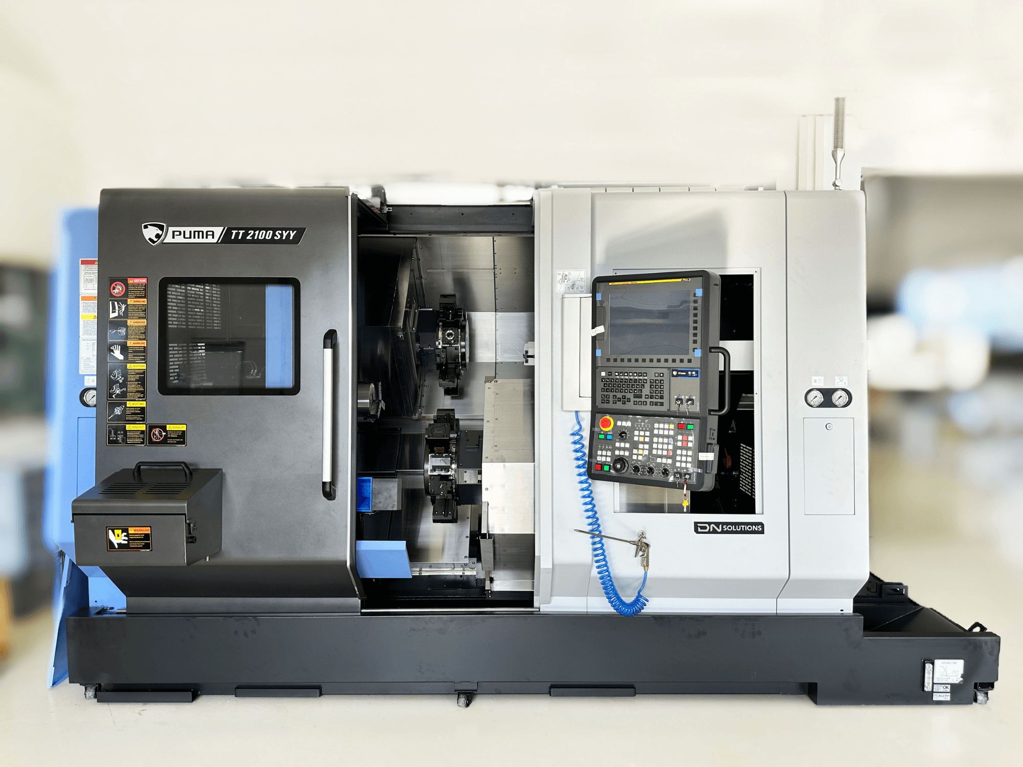 Esztergályozó központ DN SOLUTIONS PUMA TT2100SYY előlnézet, a vezérlőpanel és a látható belső alkatrészek.
