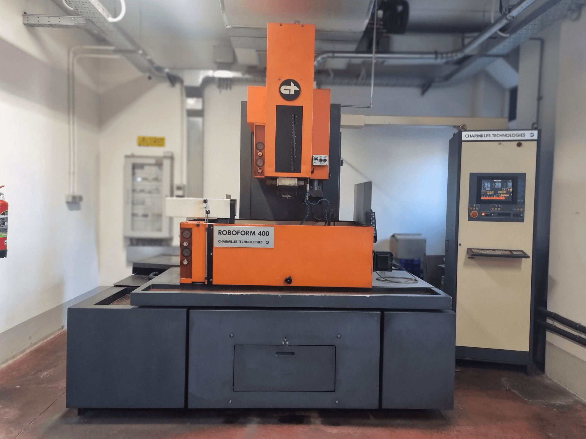 A Charmilles Technologies Roboforn 400 gép, elölnézetben, narancssárga és szürke színben, látható a digitális vezérlőpanel.