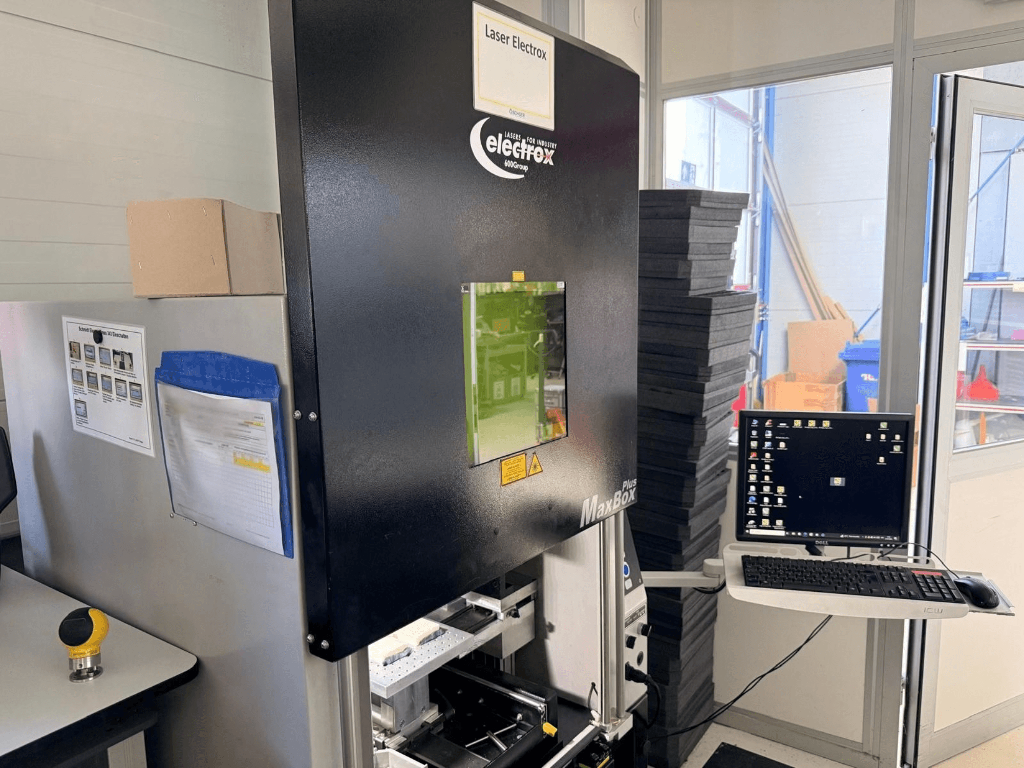 Az ELECTROX MaxBox Plus lézeres jelölőgép oldalnézetben, vezérlőképernyővel, zöld megtekintőablakkal és munkaterülettel.