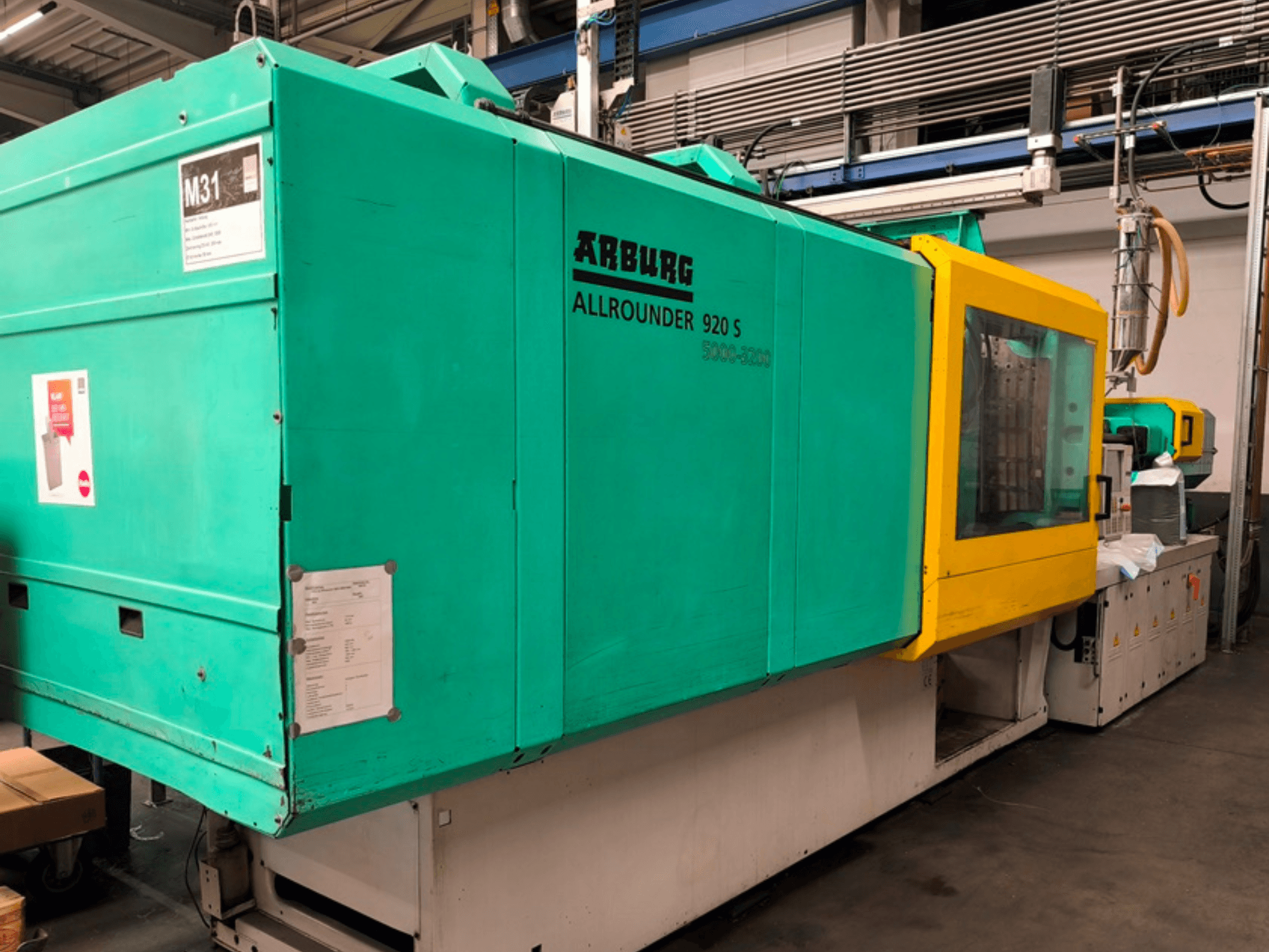 Arburg Allrounder 920 S fröccsöntőgép aquakék és sárga színben, oldalnézetben a vezérlőpanel és az alkatrészek.