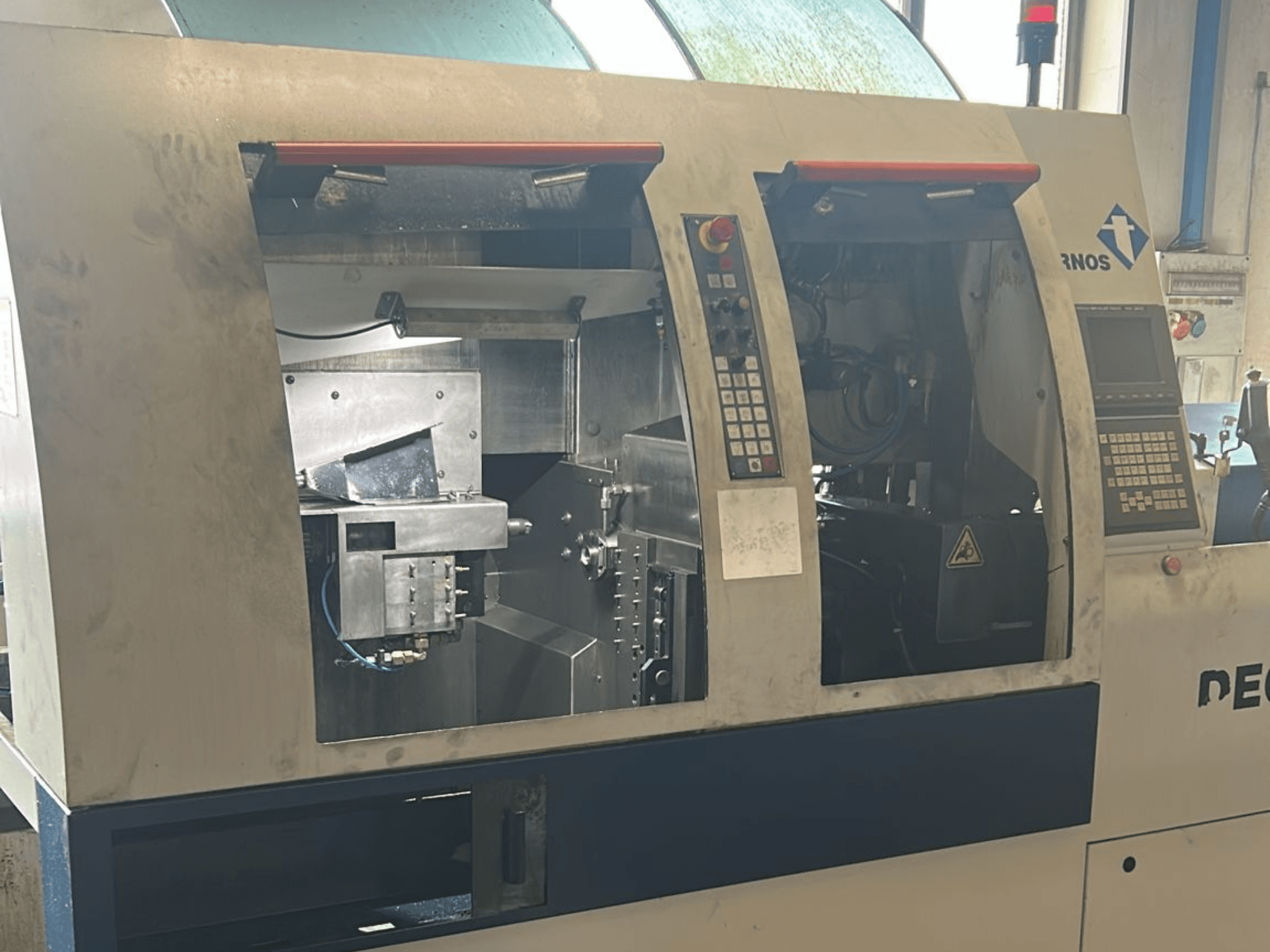 Alt szöveg: TORNOS Deco 13 b svájci típusú esztergagép előlapja, a vezérlőpanelekkel és a belső alkatrészekkel.