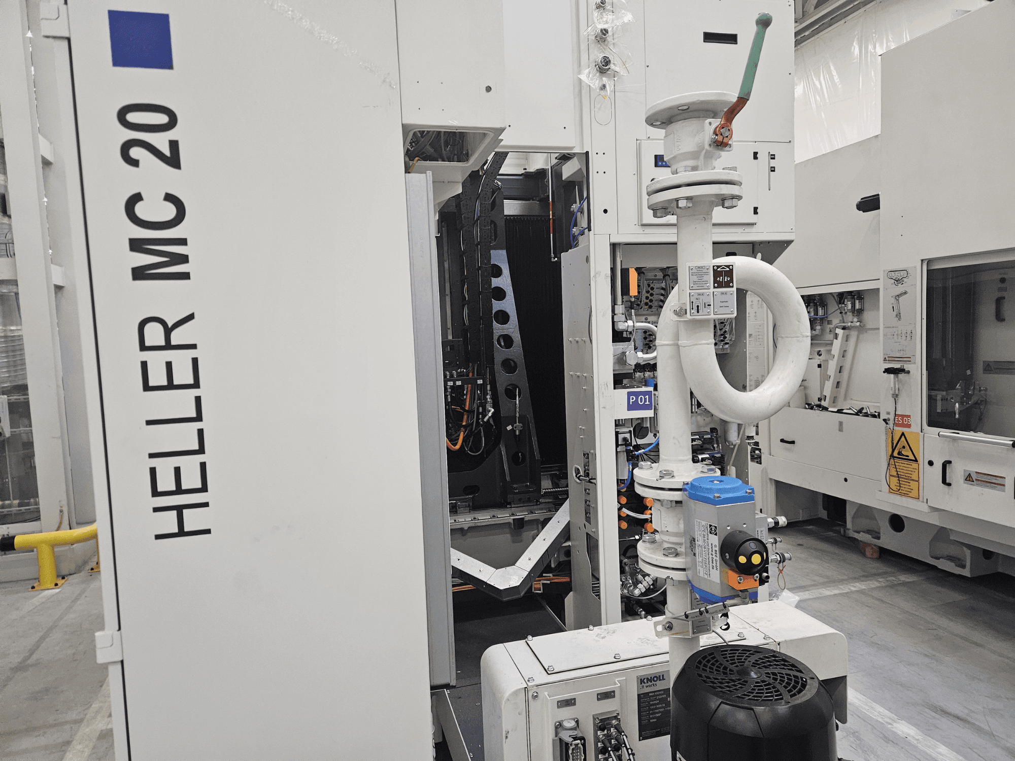 Heller MC 20 gép gyári környezetben, a vezérlőpanel és a mechanikus alkatrészek oldalnézetből.