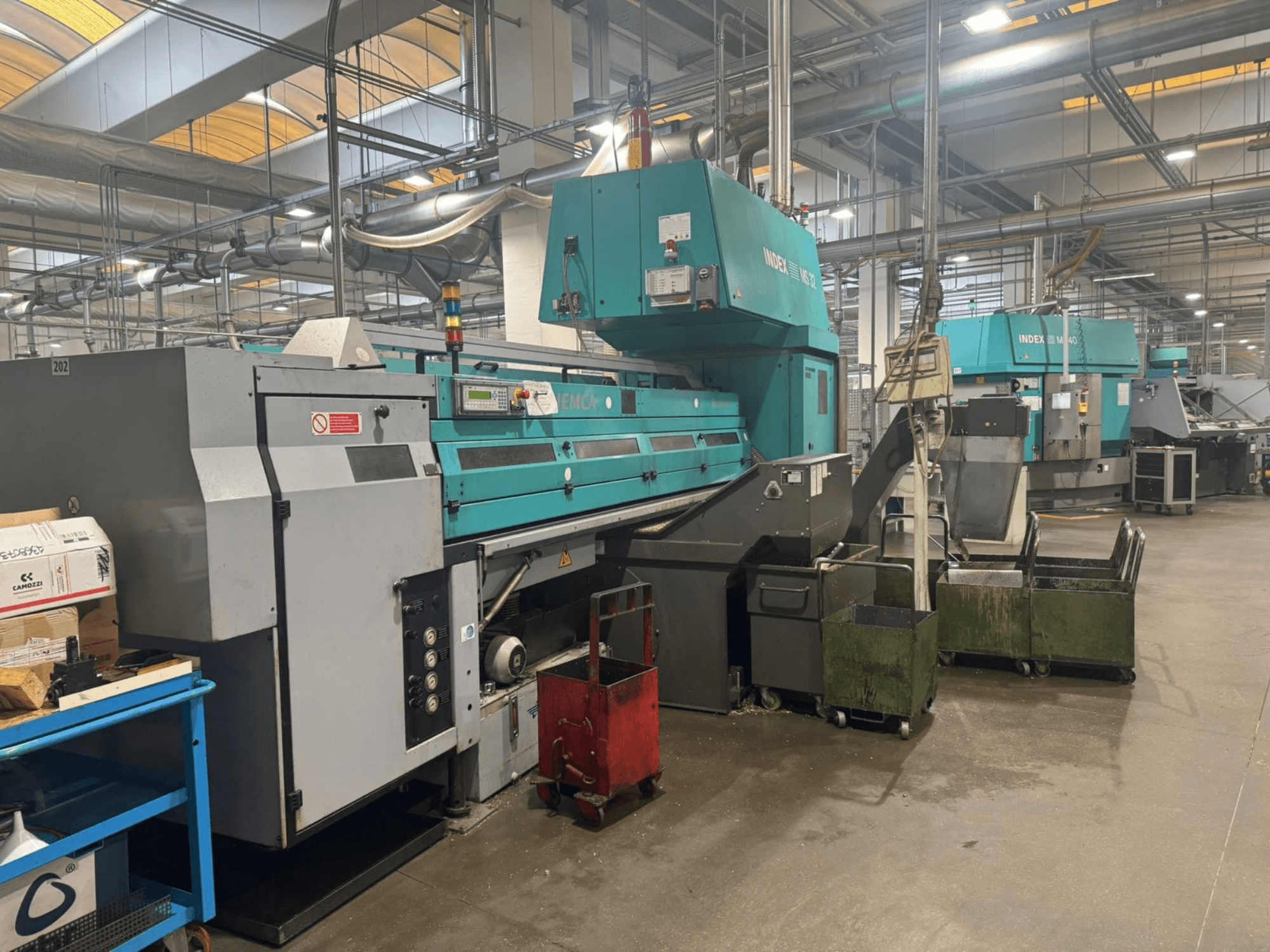 Többorsós esztergagép, INDEX MS32C, elölnézetben a kezelőszervek és a munkaterület műhelyben.