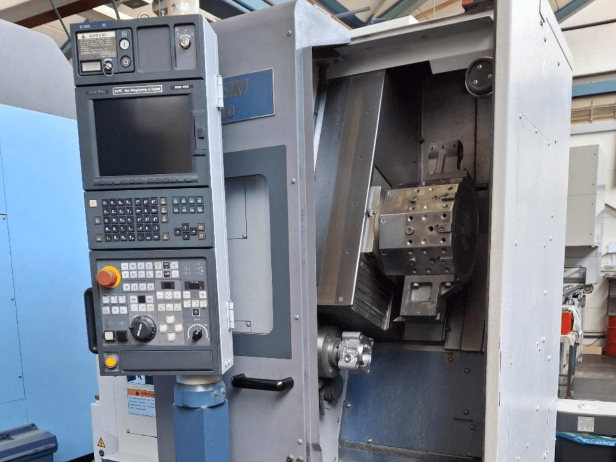 MORI SEIKI SL 1000 vízszintes esztergagép előlnézetben, a vezérlőpanel és a részletes belső mechanizmusok.