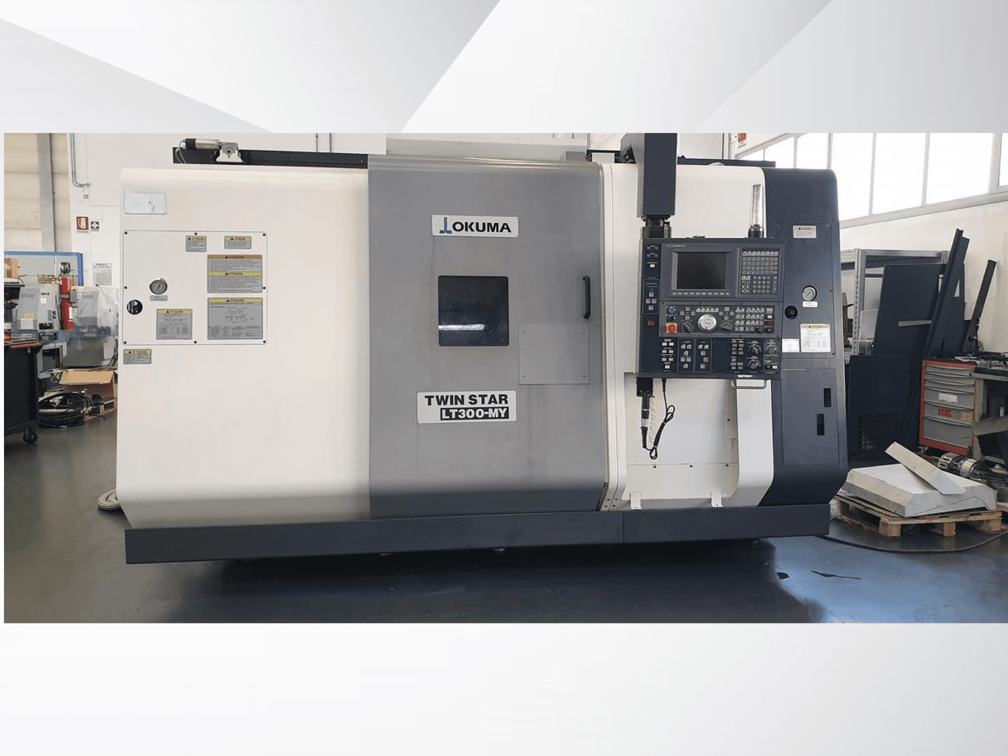 Okuma Twin Star LT300-MY CNC esztergagép, előlnézet a vezérlőpanellel és a működési címkékkel.