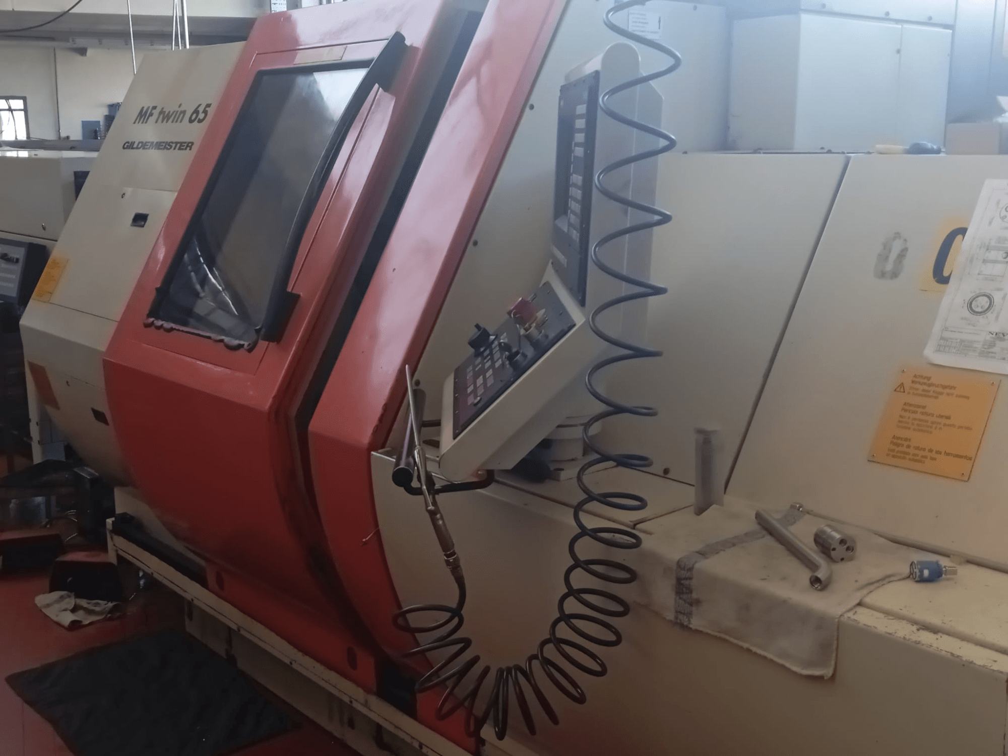 Narancssárga-fehér MF twin 65 Gliedemeister gép, elölnézetben, vezérlőpanel és szerszámok egy ruhán.