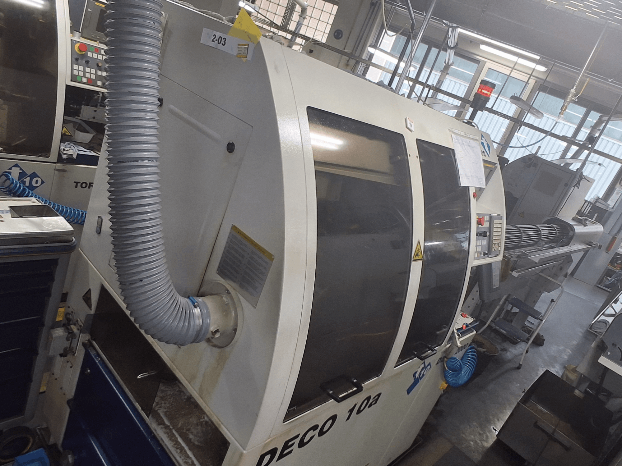 DECO 10a gép elölnézetben; látható a nagyméretű vezérlőpanel, a csatornák és a működési matricák.