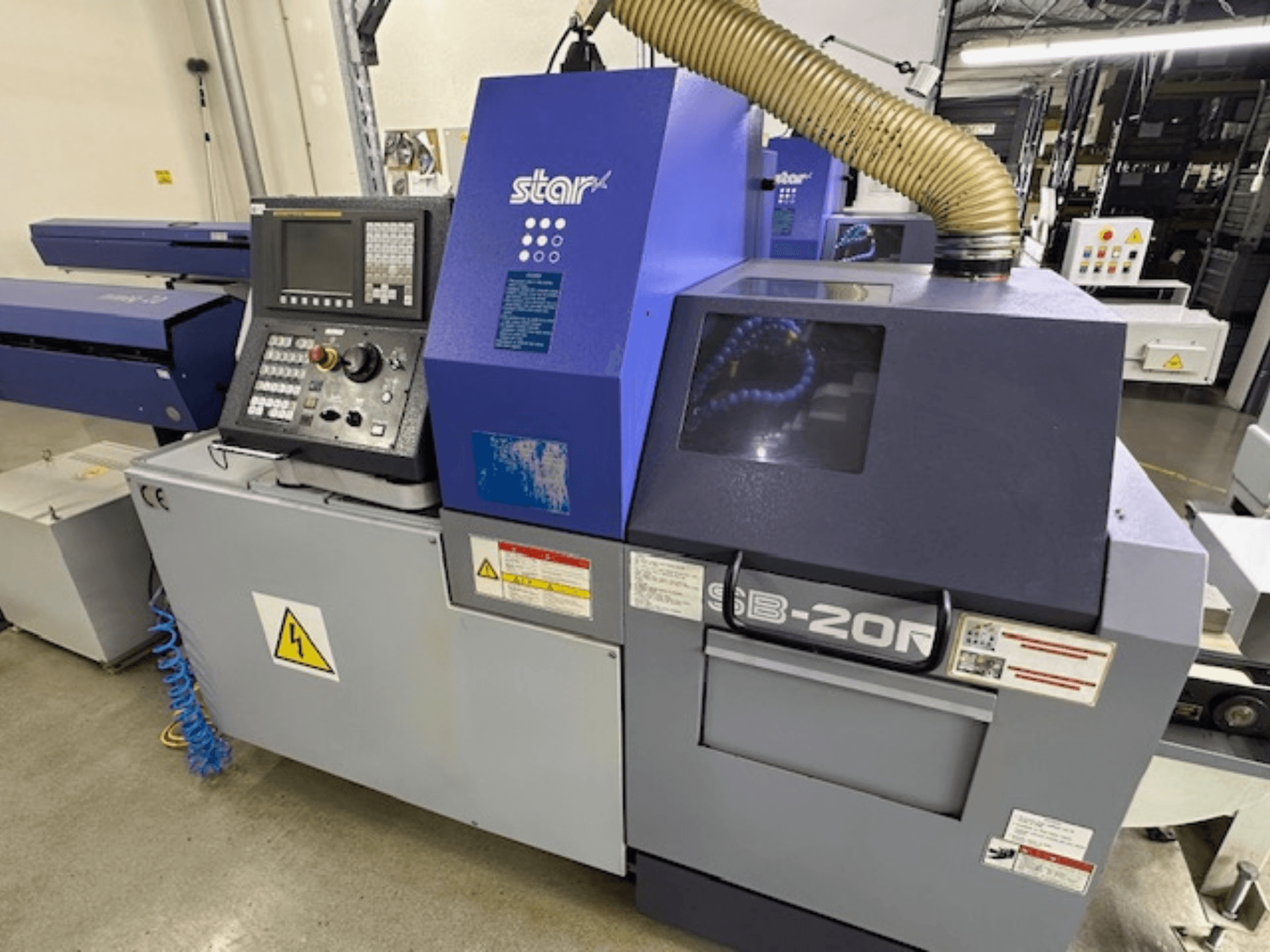 Star SB-20R típusú N svájci típusú esztergagép, elölnézetben, vezérlőpanellel, szívótömlővel és látható veszélyszimbólumokkal.