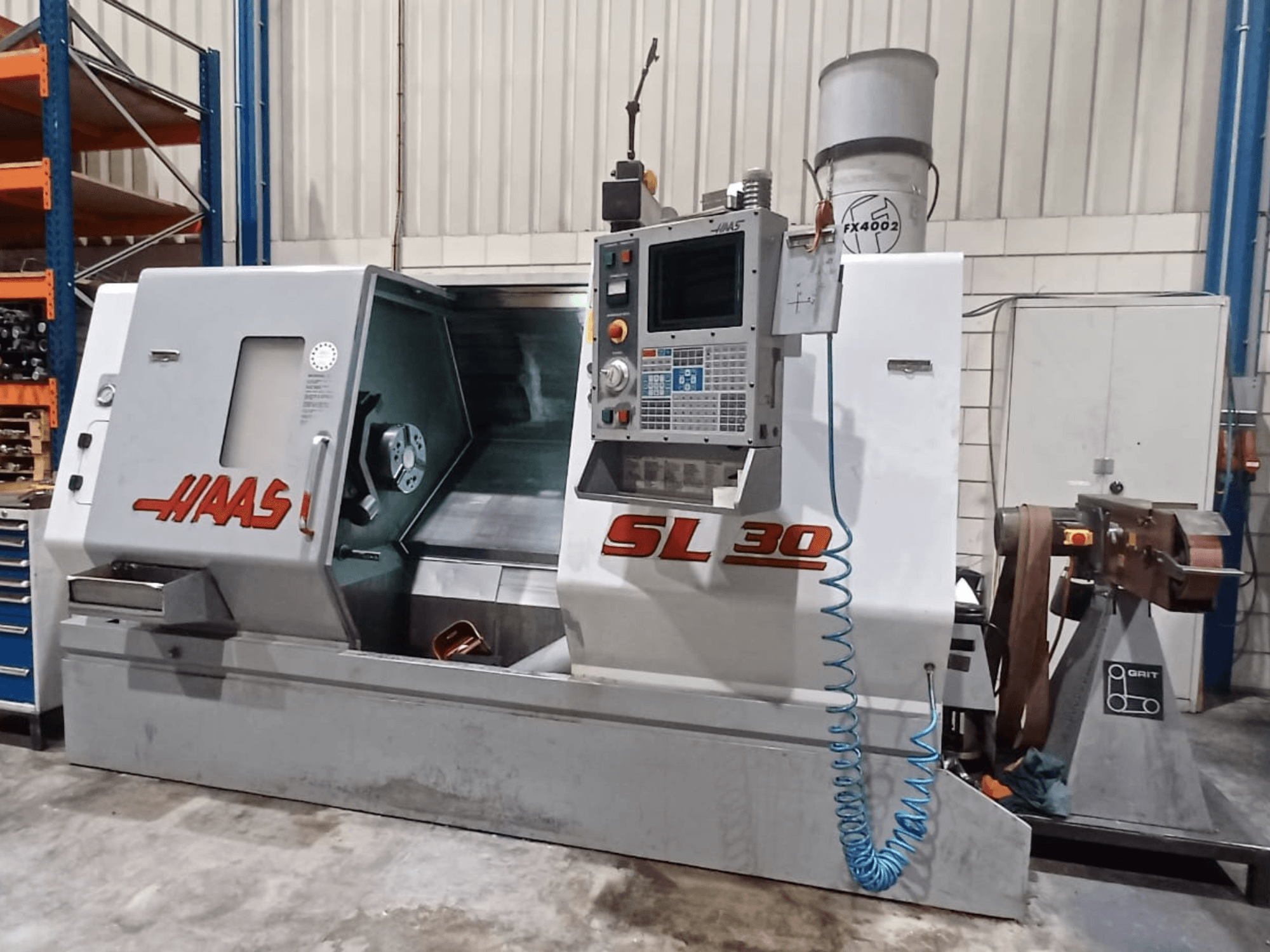 Haas SL 30 CNC eszterga oldalnézetben, a vezérlőpanel, a megmunkálási terület és a fémmegmunkáláshoz integrált hűtőfolyadék-rendszer bemutatásával.