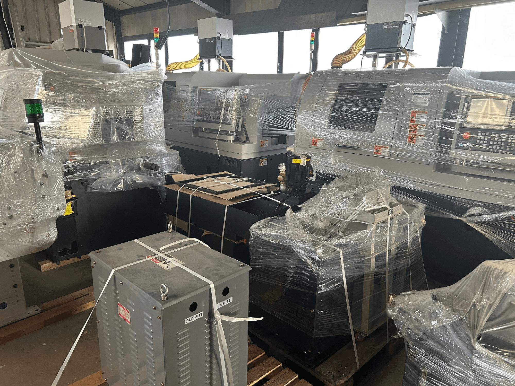 Hanwha XD20V kombinált svájci típusú esztergagép, részben becsomagolva, oldalnézetből, a vezérlés és a gépelemek láthatóak.