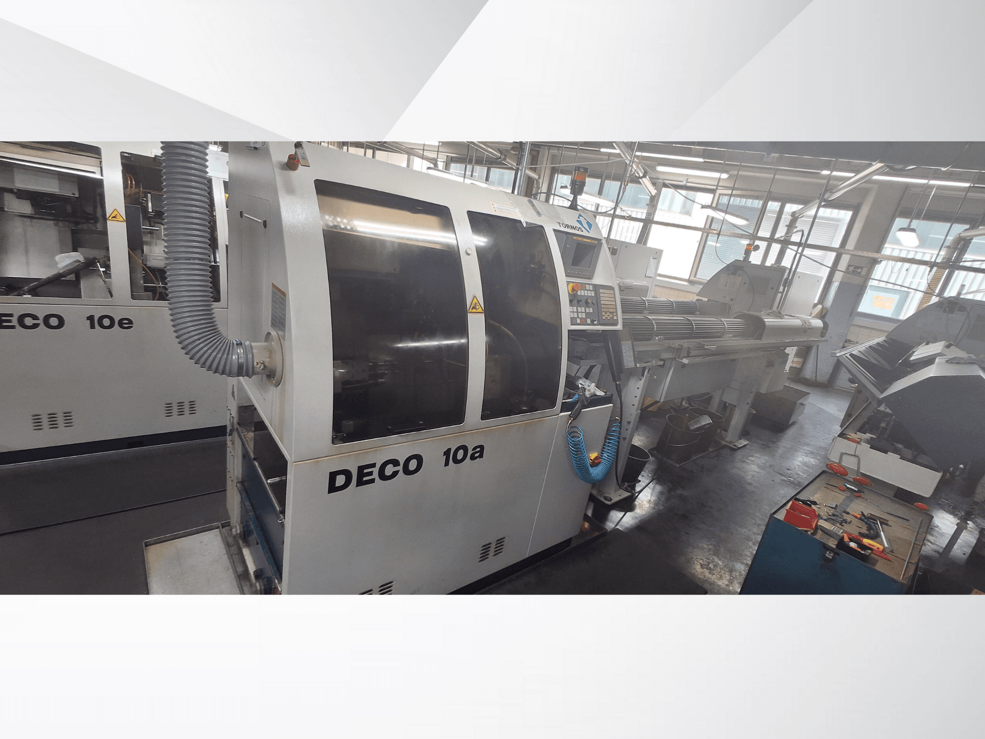 DECO 10a CNC-gép egy műhelyben, előlap, vezérlőpanel és kipufogórendszer. Robusztus felépítés és precíziós szerszámok jellemzik.