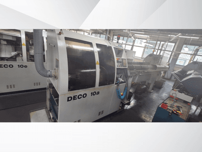 DECO 10a CNC-gép egy műhelyben, előlap, vezérlőpanel és kipufogórendszer. Robusztus felépítés és precíziós szerszámok jellemzik.