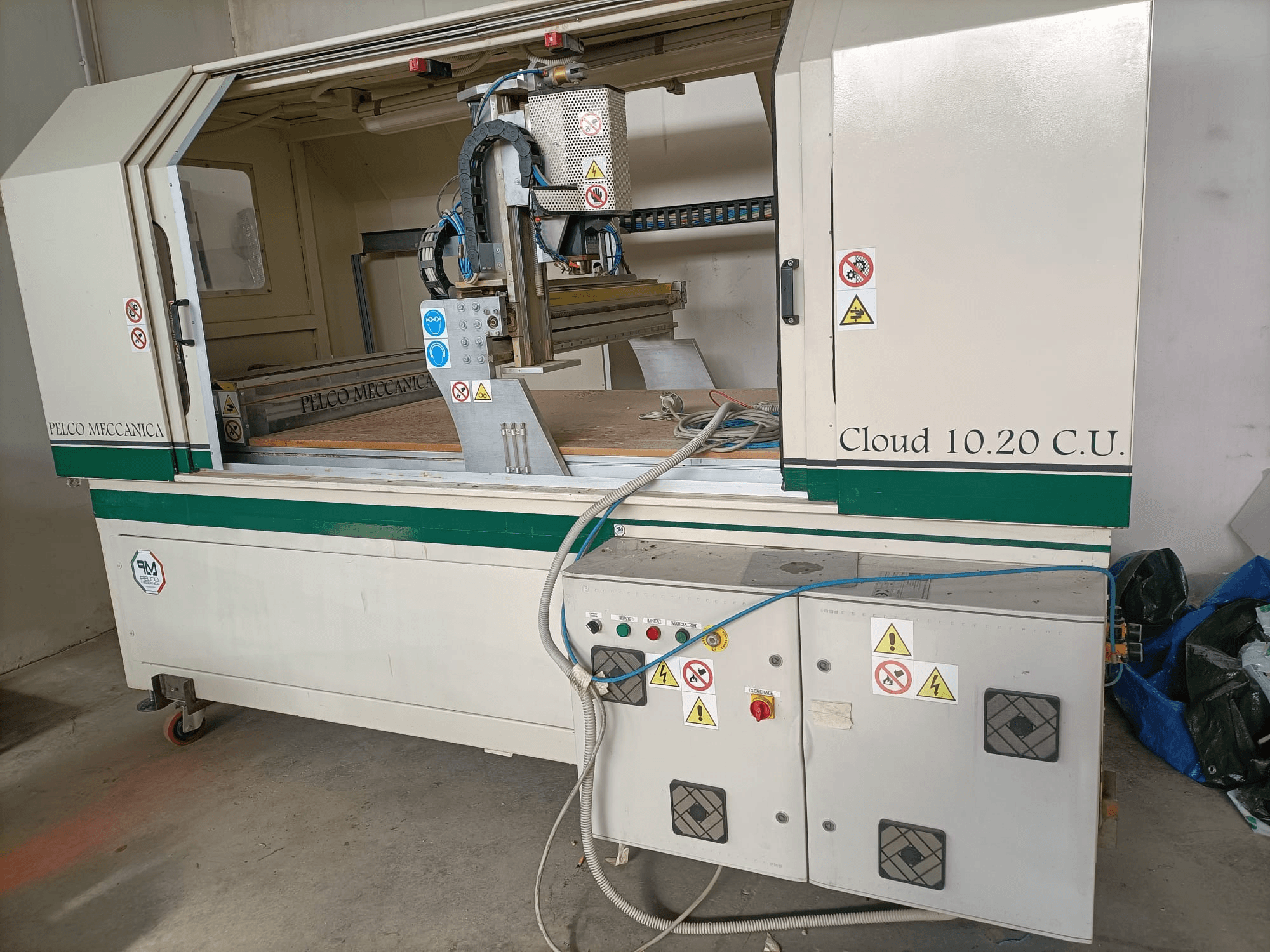 CNC router MECCANICA CLOUD 10.20 C.U., elölnézetben a kezelőpanel és a munkaterület, láthatóak a biztonsági címkék és a tömlők.