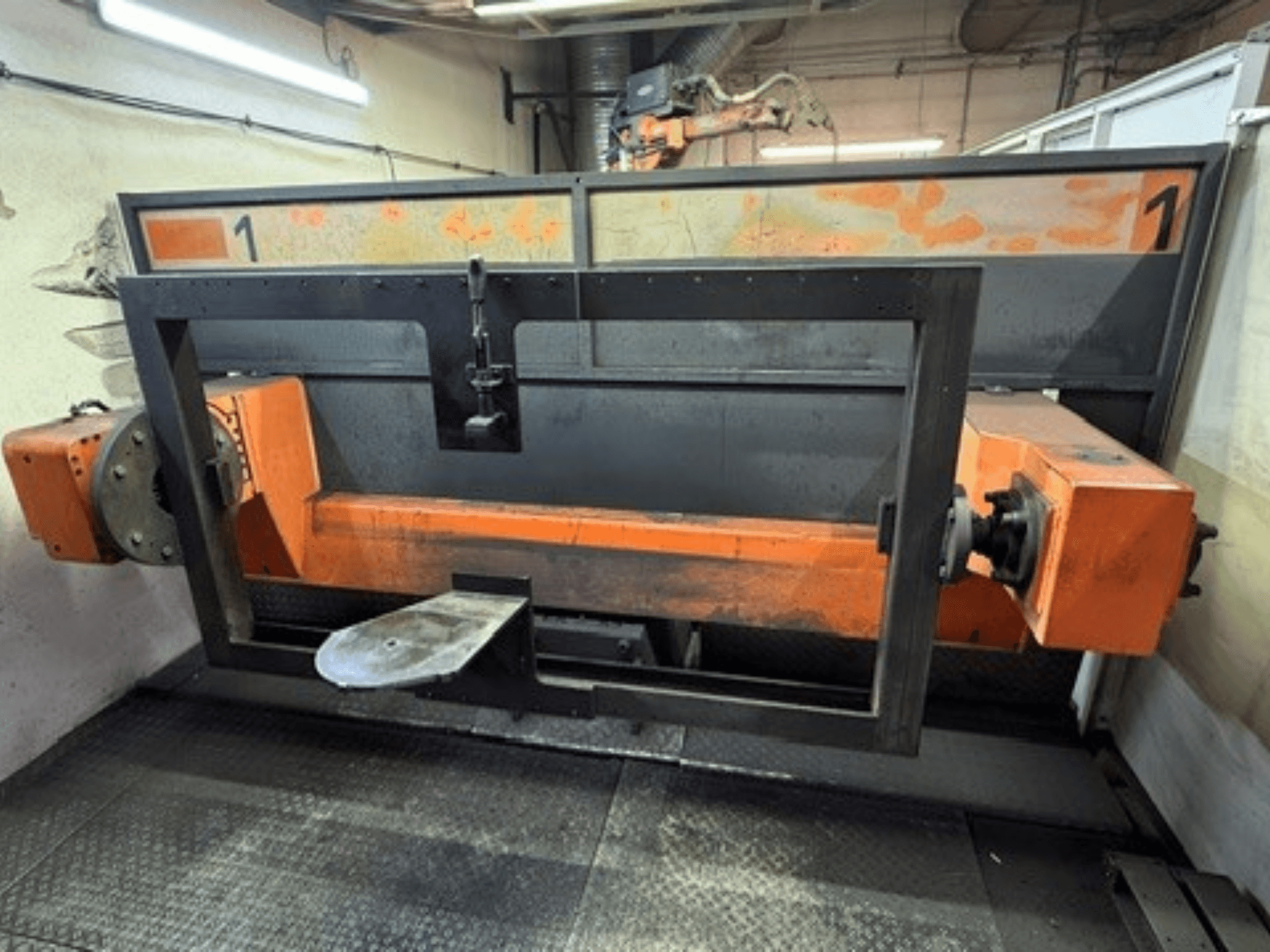 Az ABB IRB 2400L hegesztőcellájának elölnézete, amelyen egy műhelyi környezetben látható egy nagy robotváz narancssárga és fekete alkatrészekkel.