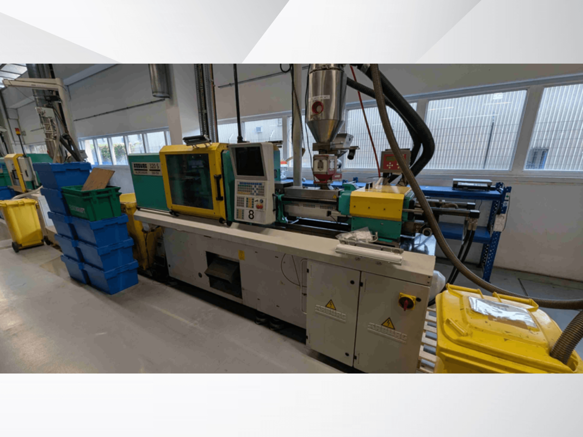 Arburg 320 S 350-150 hidraulikus fröccsöntőgép, elölnézet, amelyen láthatók a kezelőszervek, az extruder és a színes anyagtartályok.