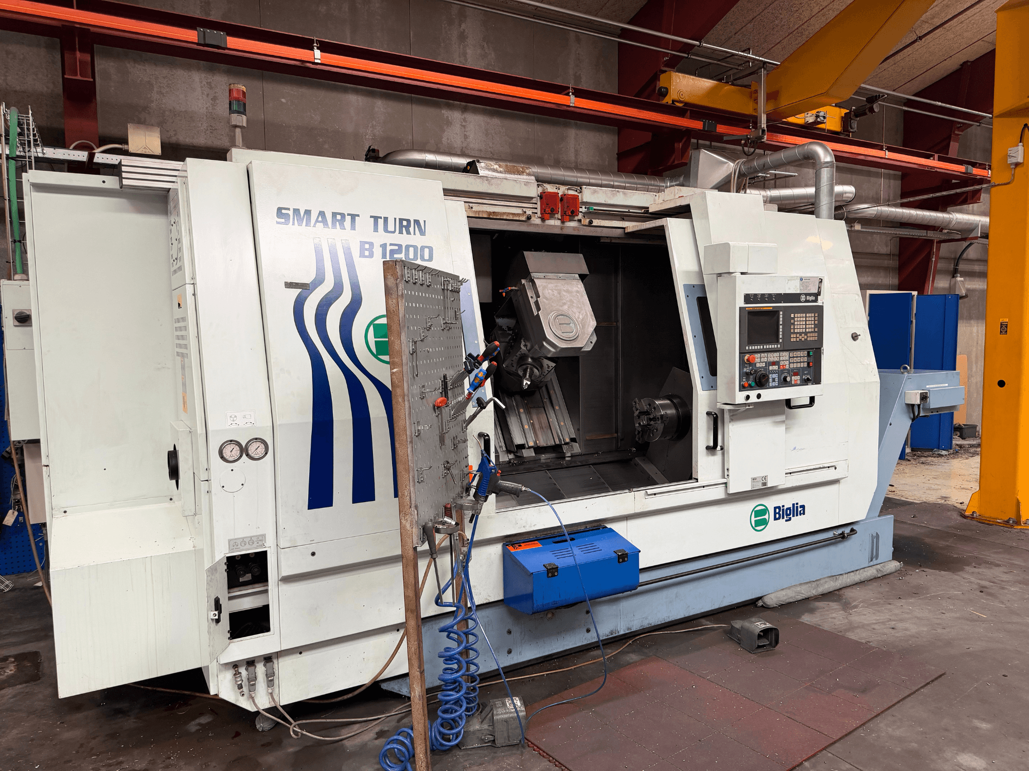 A Biglia B.1200/S-Smart eszterga-marógép elölnézete; a képen láthatóak a kezelőszervek, a főorsóban lévő munkadarab és a nyomásmérők.