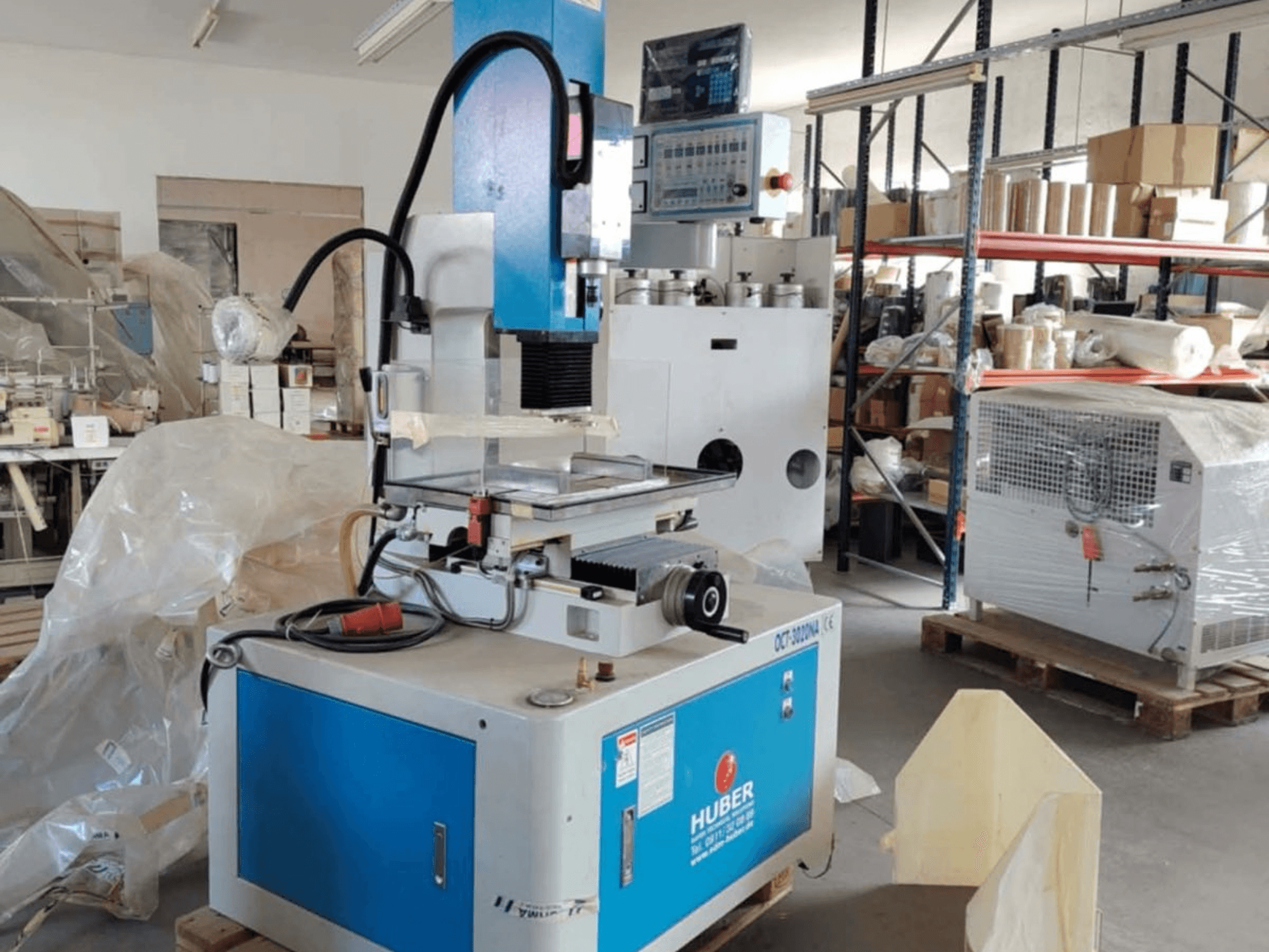 HUBER OCT-3020 NA süllyesztéses süllyesztéses szerszámmaró gép egy műhelyben, elölnézetben a kék és szürke burkolat, a digitális vezérlés és a munkaterület.